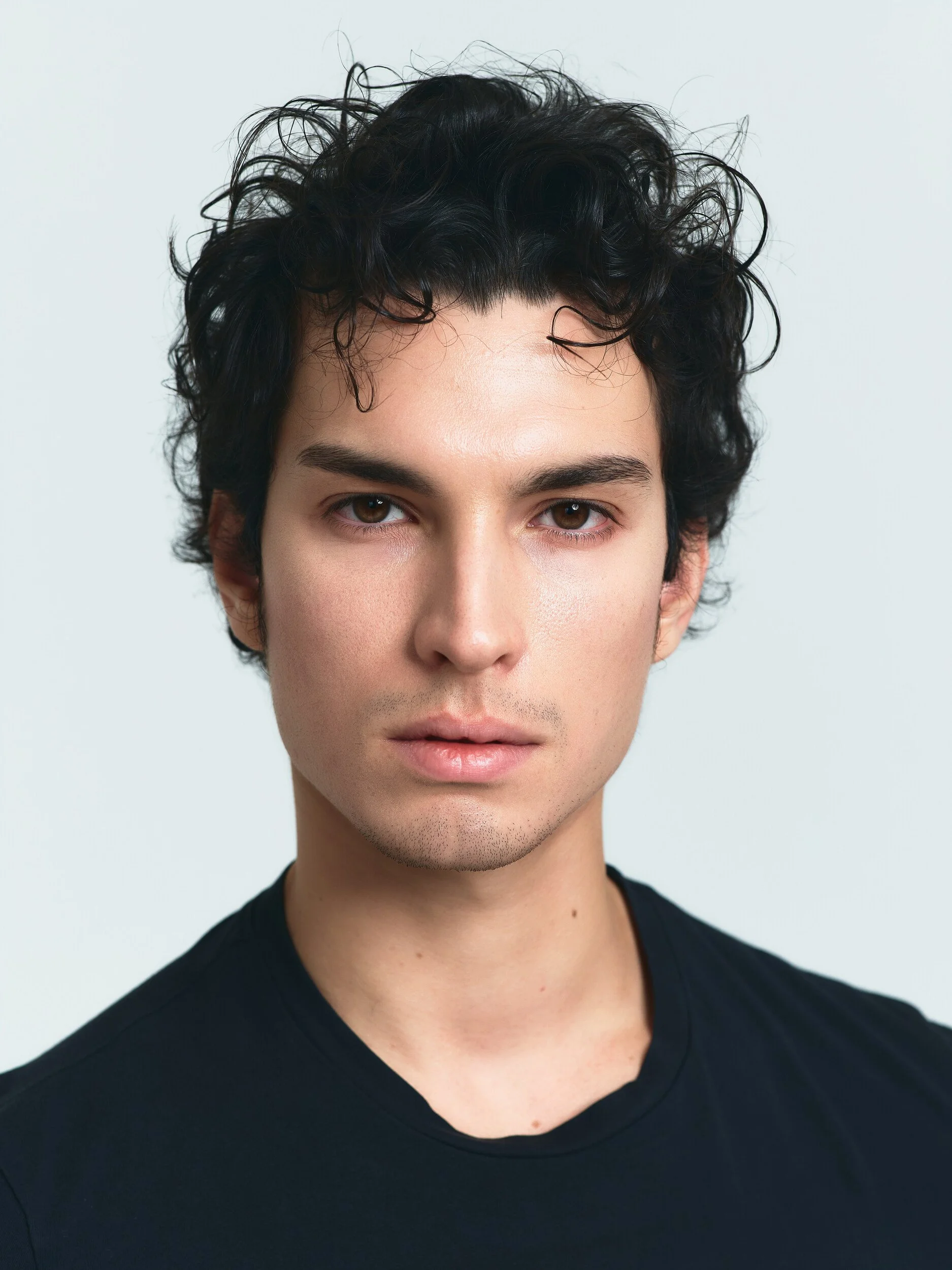 Model digitals: close-up of a man with dark curly hair in a black T-shirt, front view