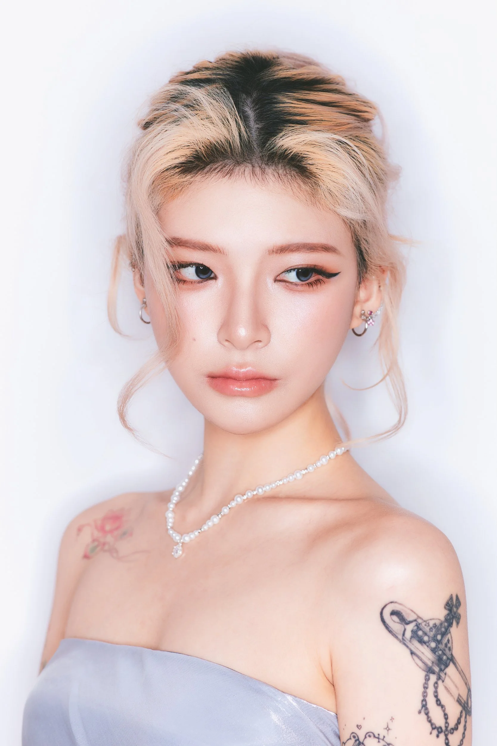 Close-up portrait of a woman with a blonde updo and tattooed shoulder