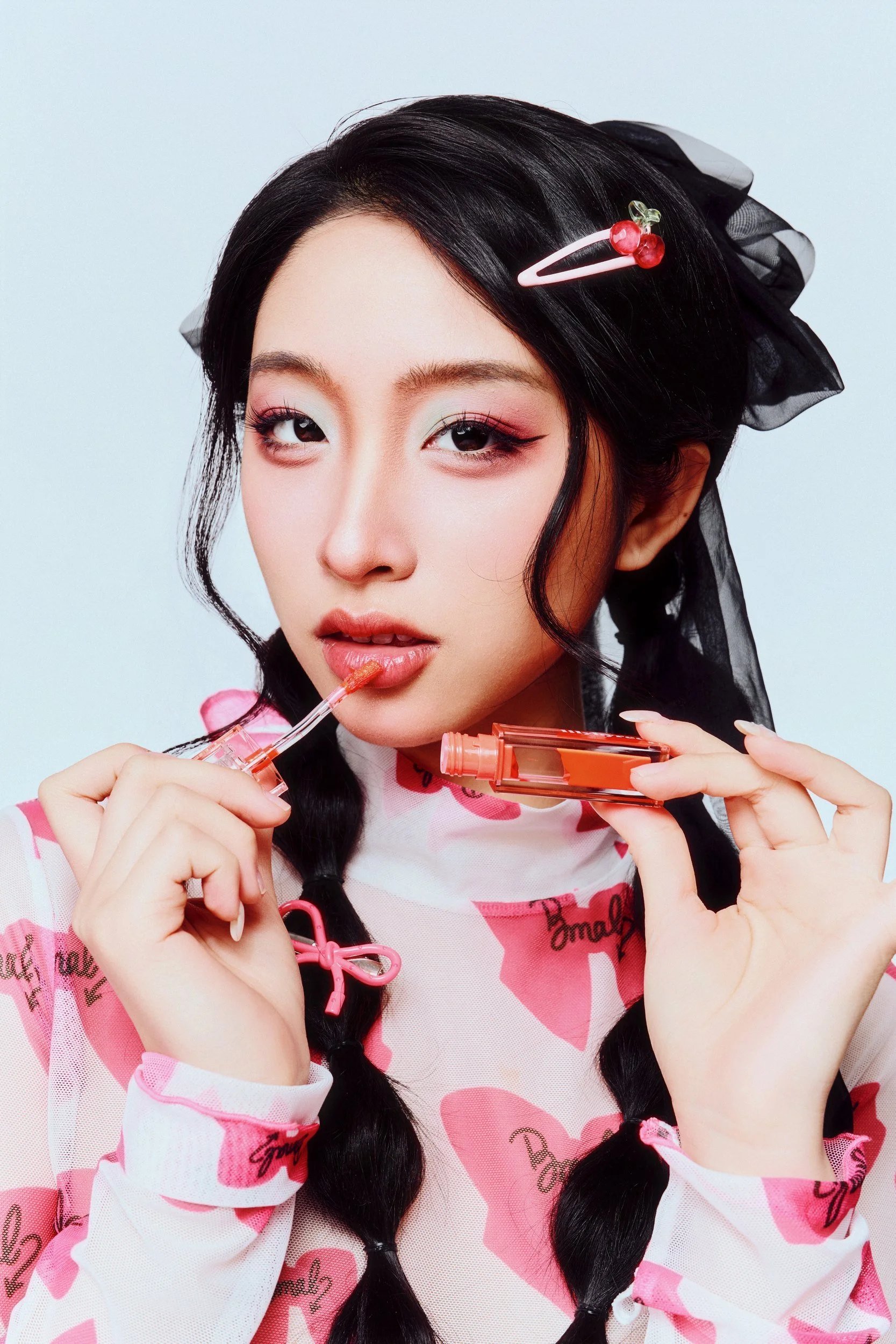 Studio portrait of a woman with braided hair in a pink bow-print top