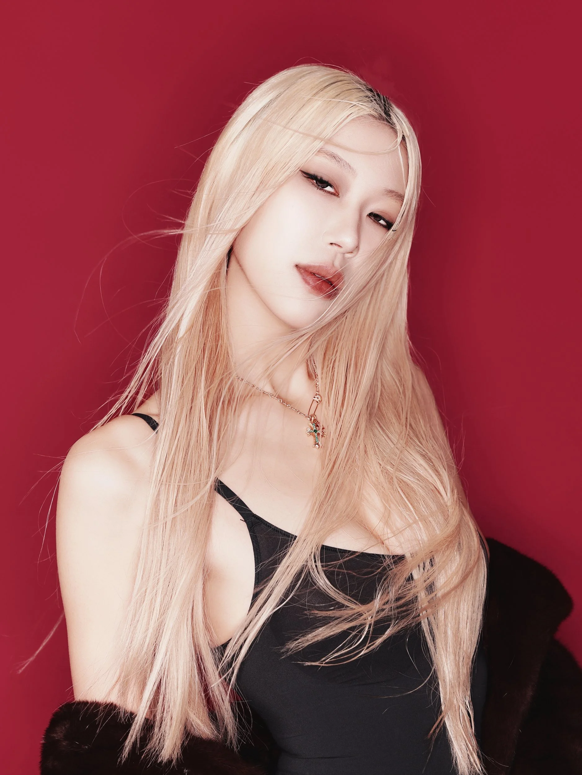 Studio portrait of a woman with platinum hair on a red backdrop