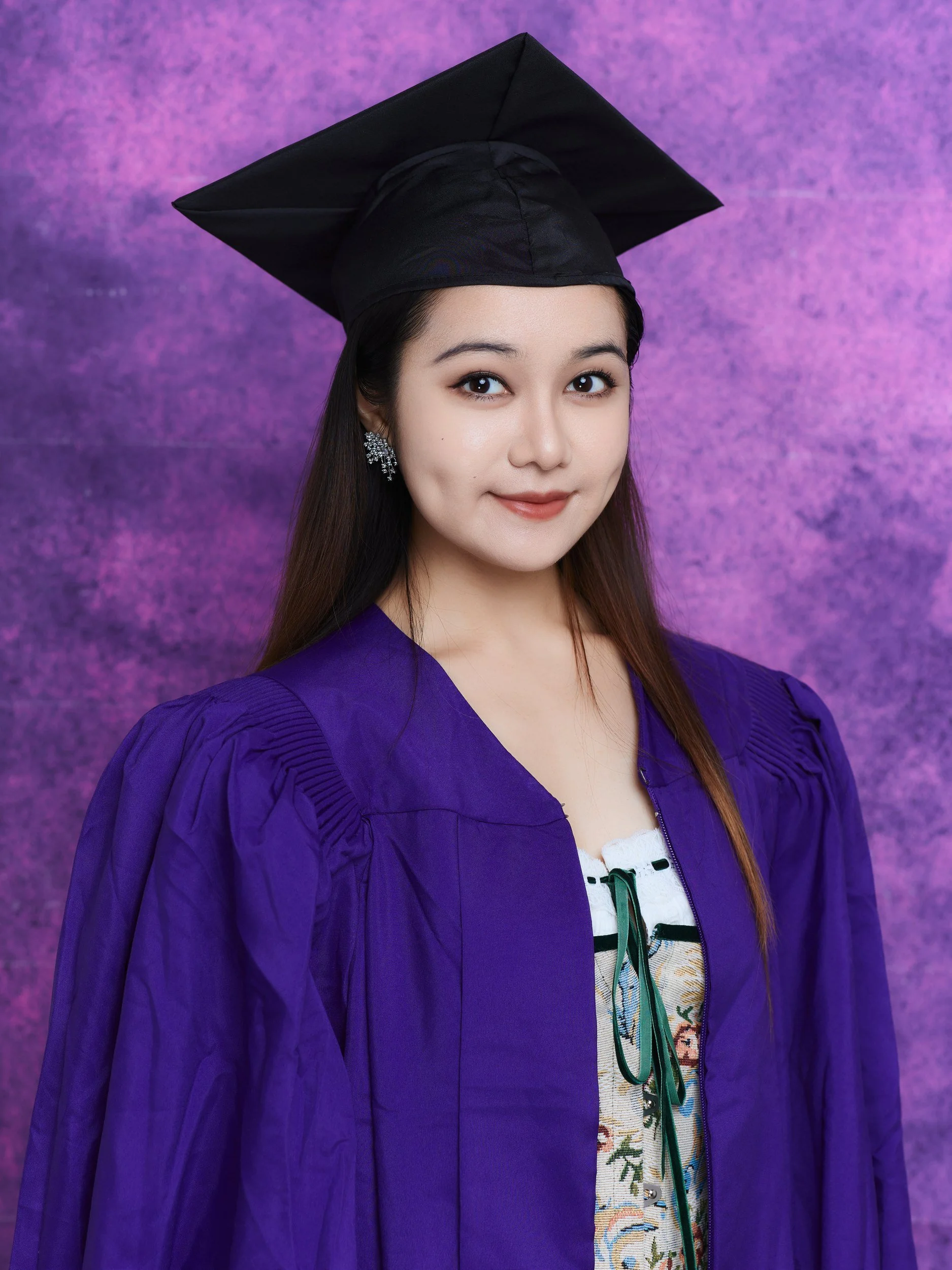 NYU graduation portrait of a woman with long hair in a purple gown and cap