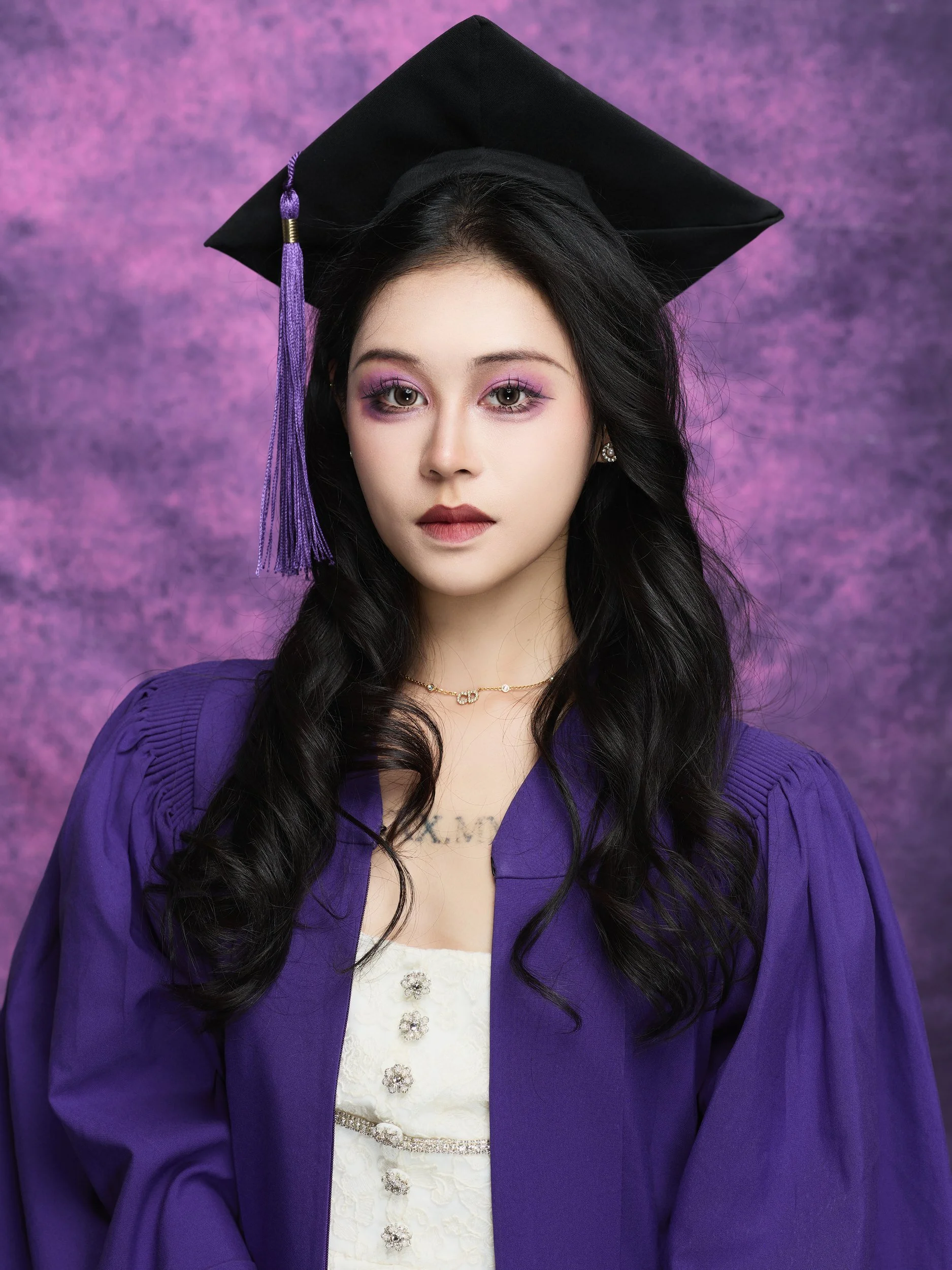 NYU graduation portrait of a woman with long hair in a purple gown and cap