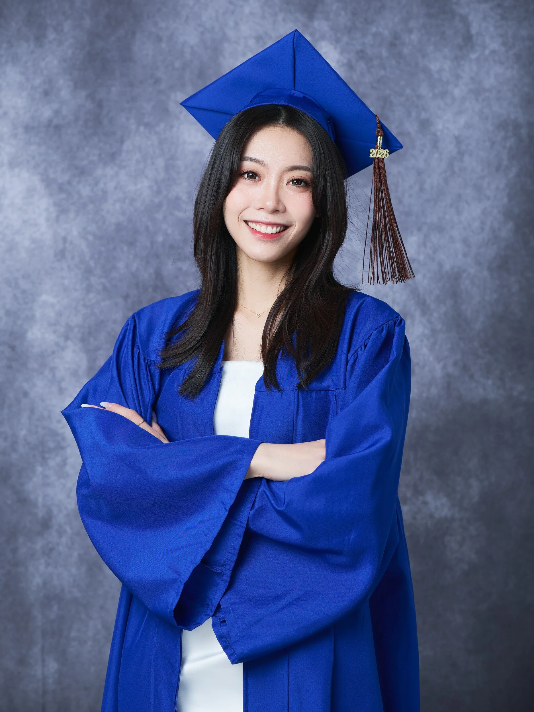 FIT graduate in a royal blue gown, arms crossed