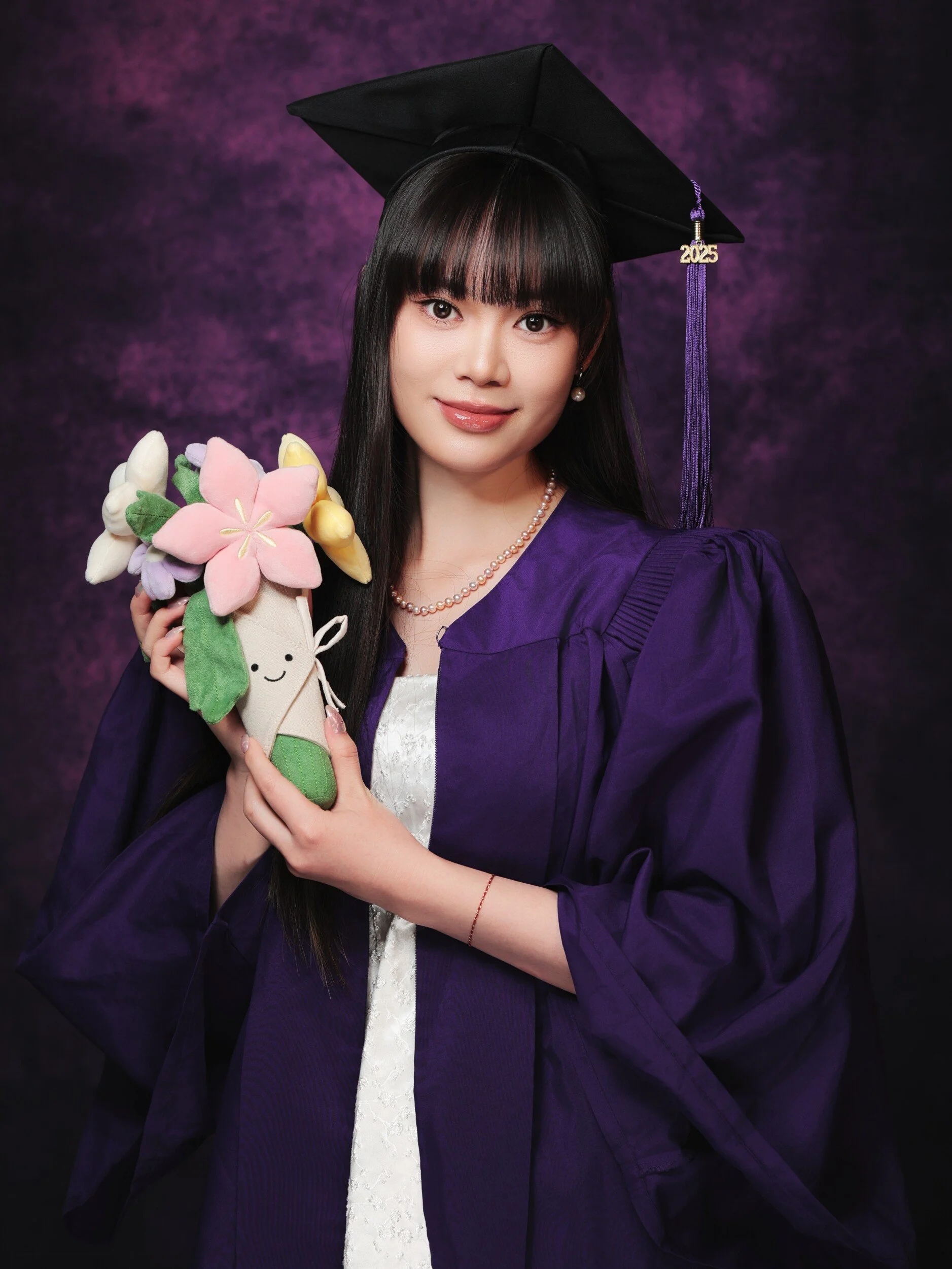 NYU graduate with bangs holding a plush flower bouquet