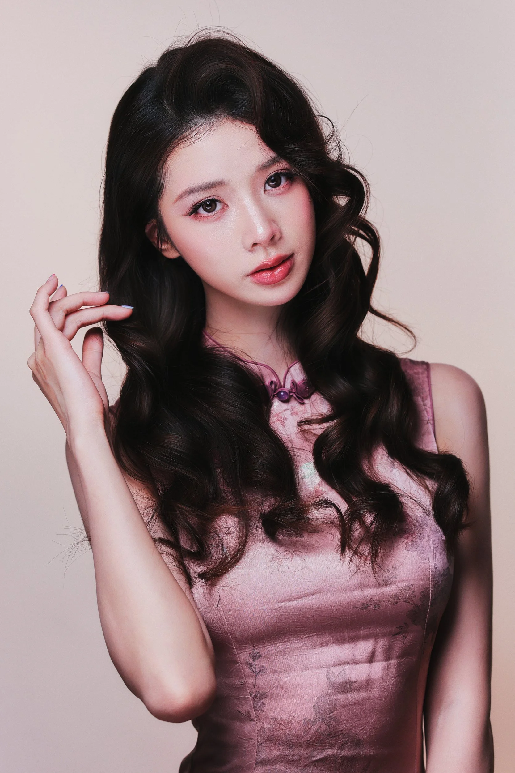 Studio portrait of a woman in a pink qipao touching her hair