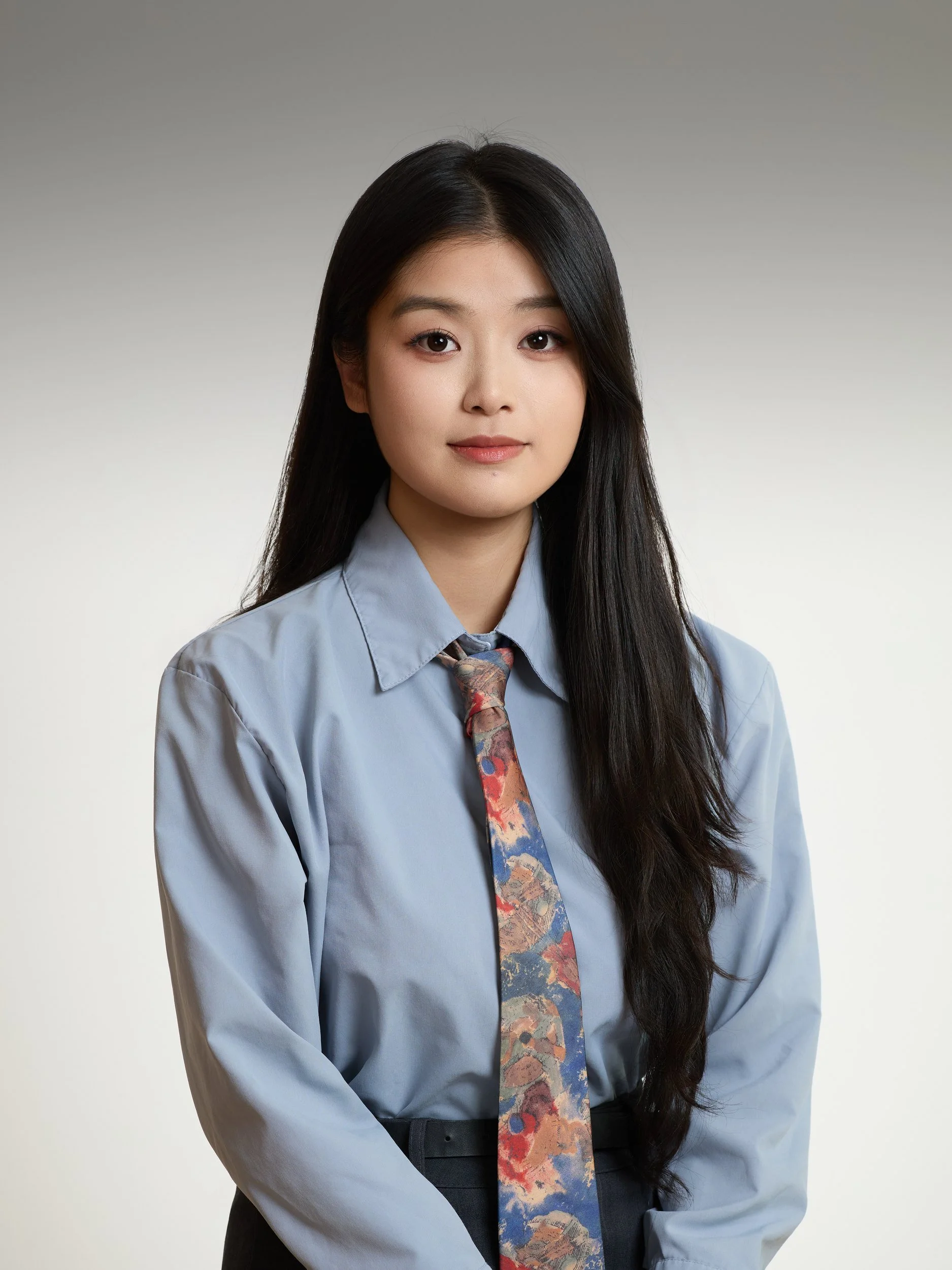 Corporate headshot of a woman in a light blue shirt and patterned tie