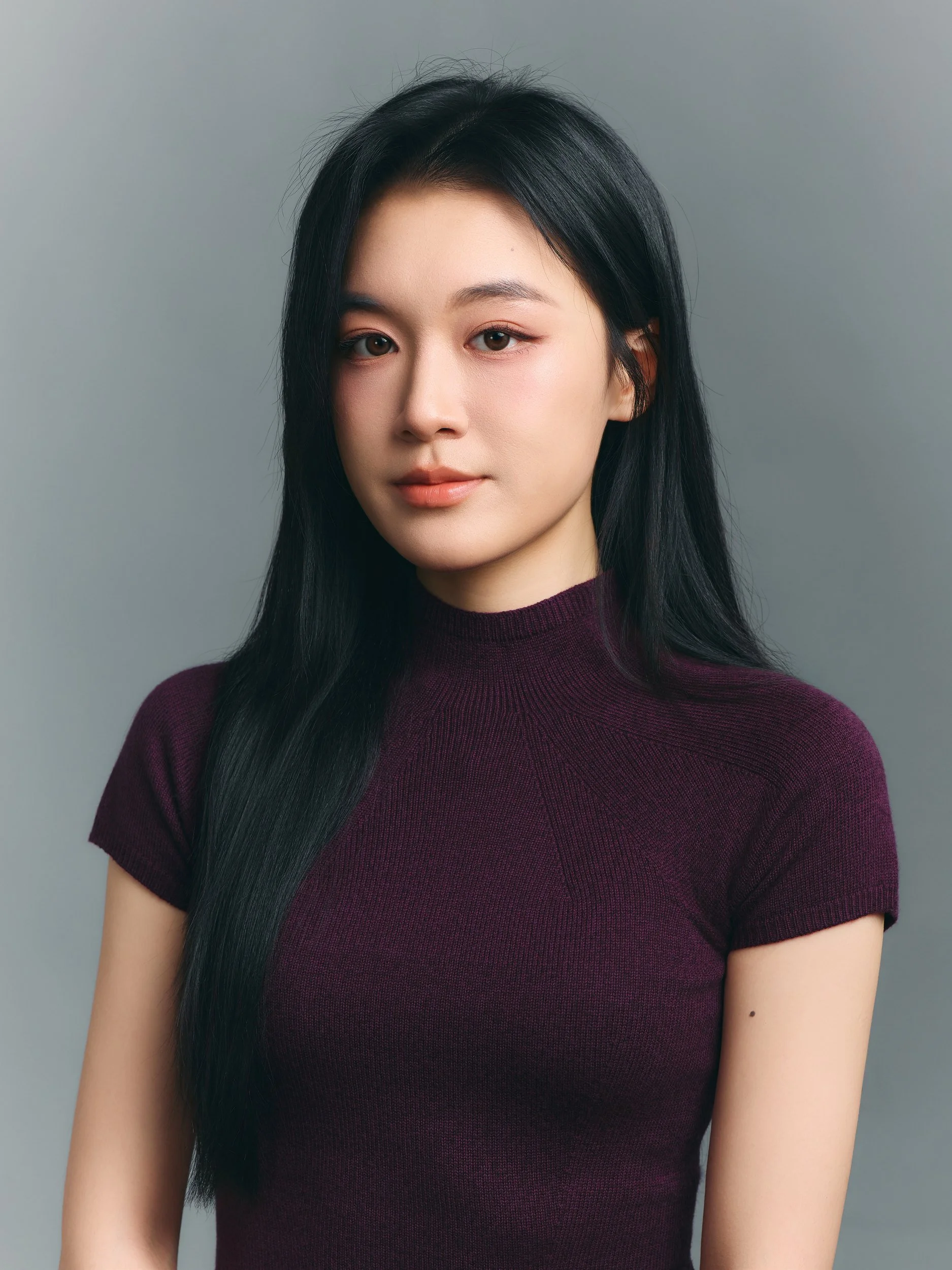 Studio portrait of a woman in a burgundy knit top on a grey backdrop