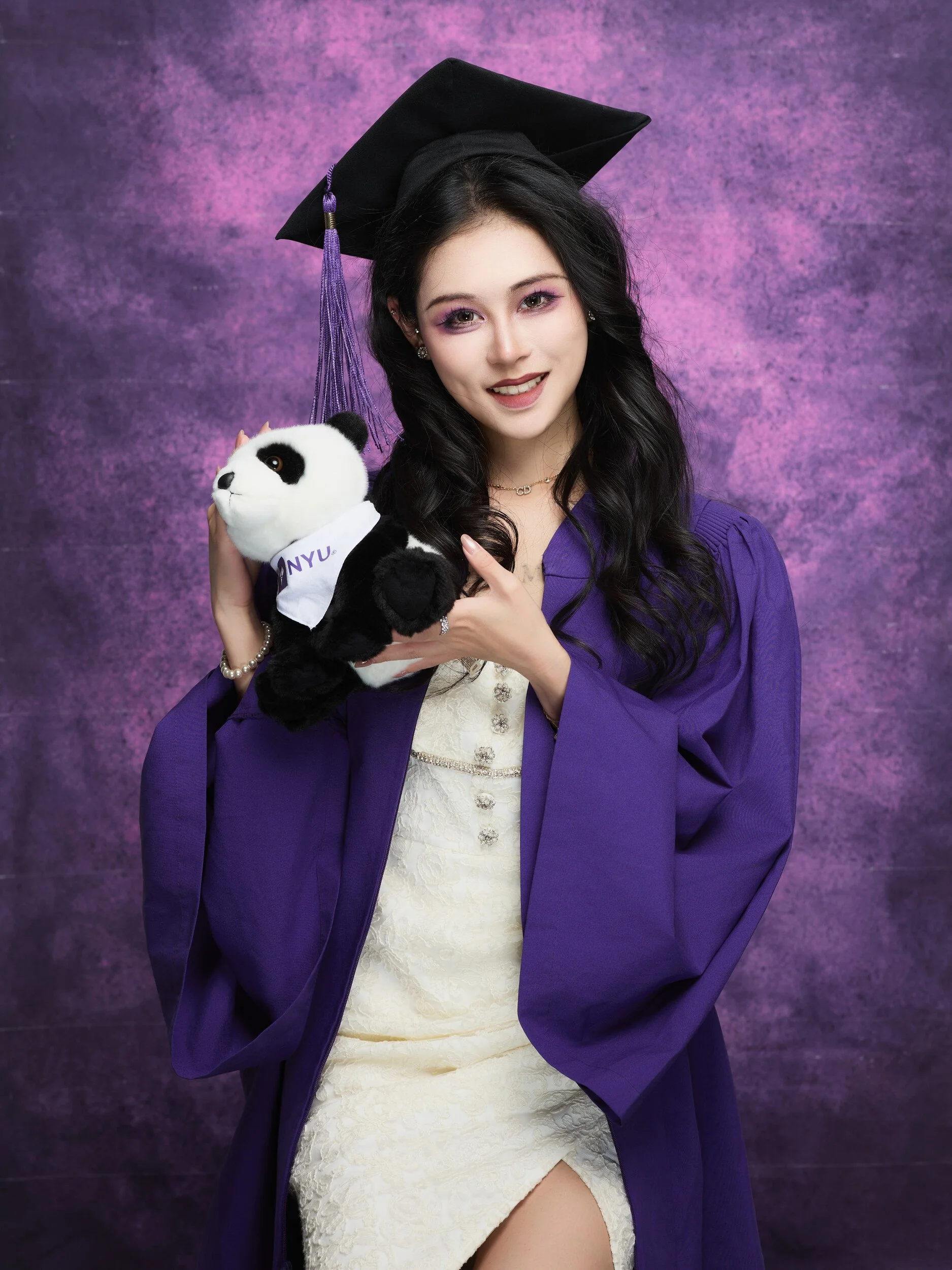 NYU graduation portrait of a woman with long dark hair holding a panda plush