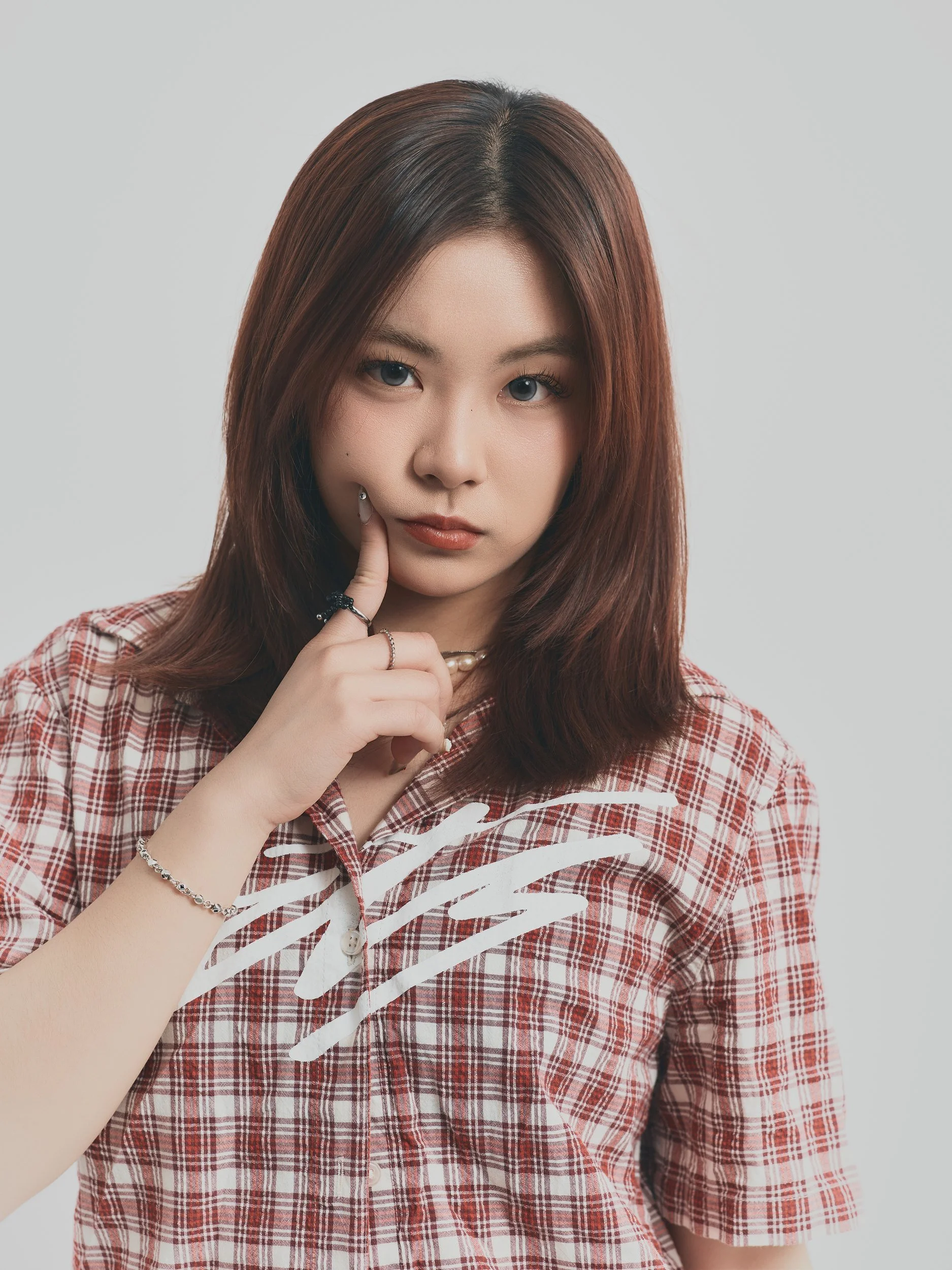 Model test close shot of a woman in a plaid shirt with a finger to her lips