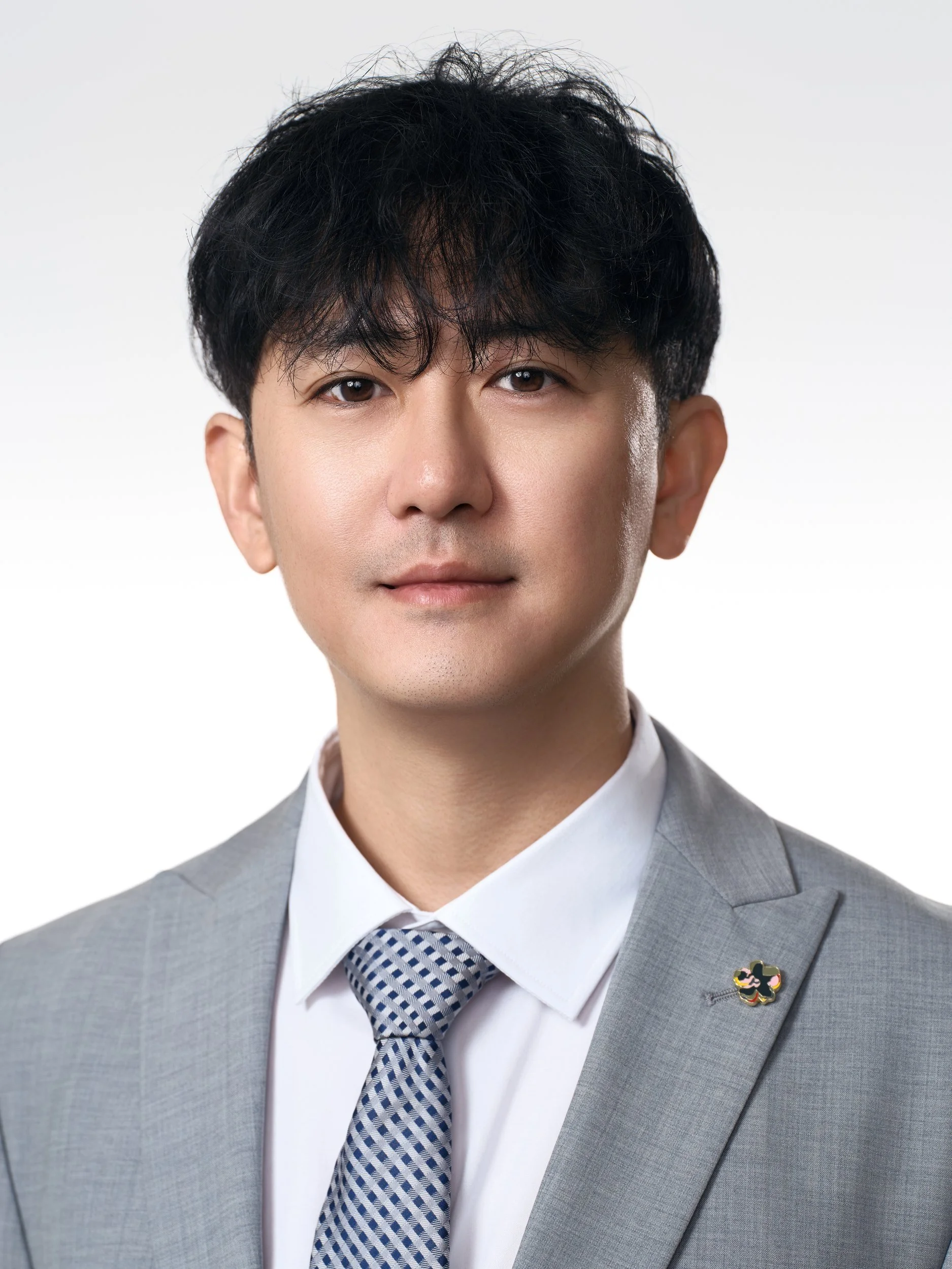 Corporate headshot of a man in a light grey suit