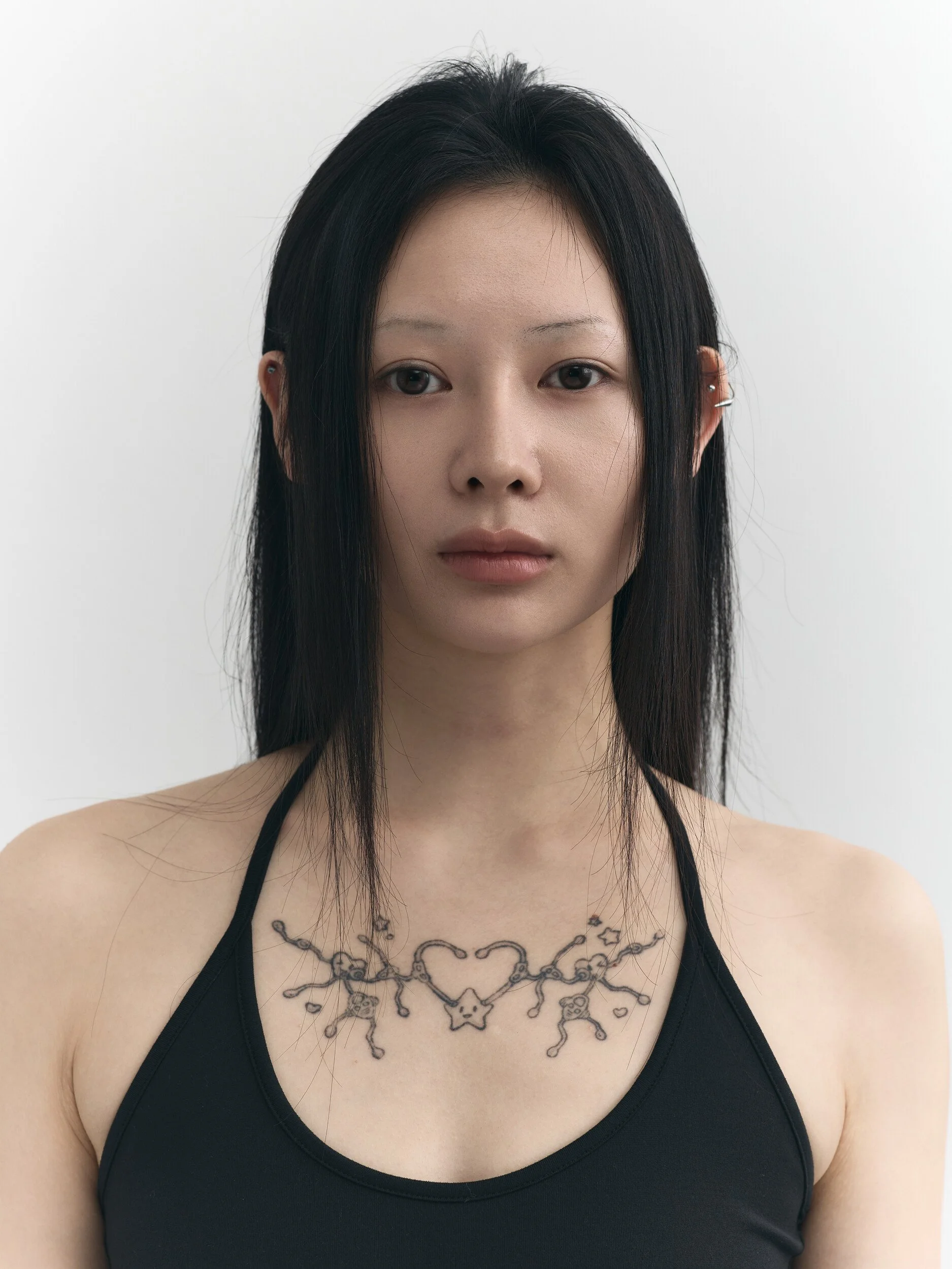 Model digitals: close-up of a woman with long black hair and a chest tattoo, front view