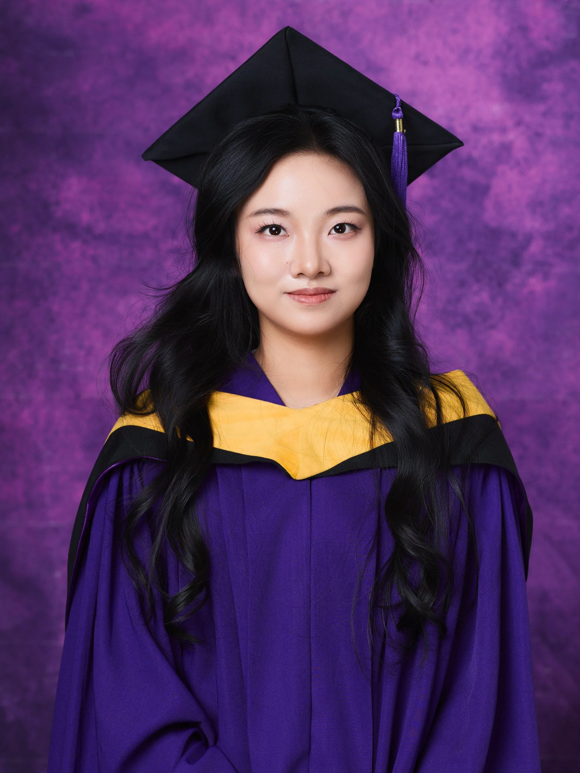 NYU graduation portrait of a woman with long dark hair in a purple gown with a yellow hood