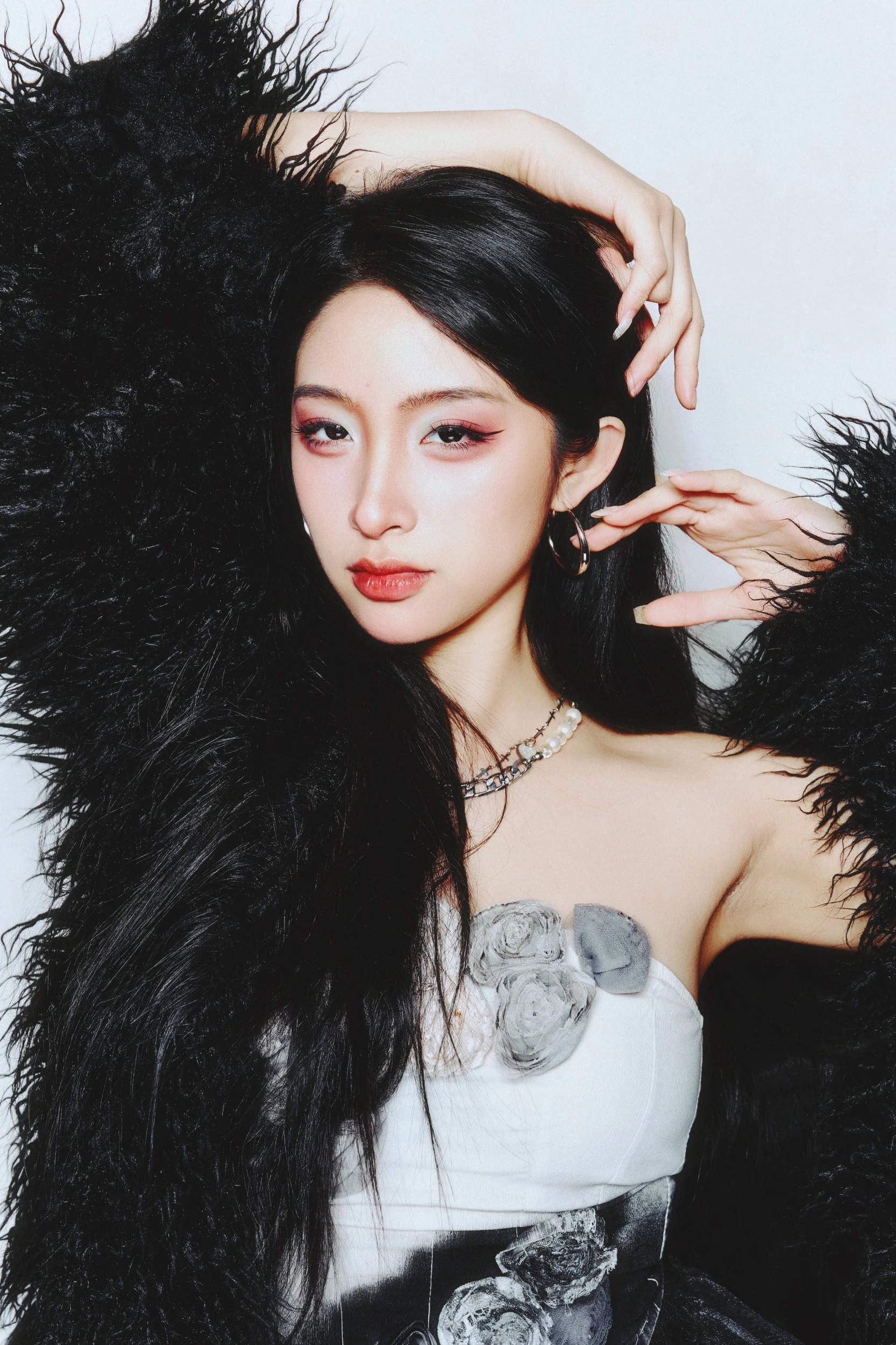 Studio portrait of a woman in black faux fur with a hand in her hair