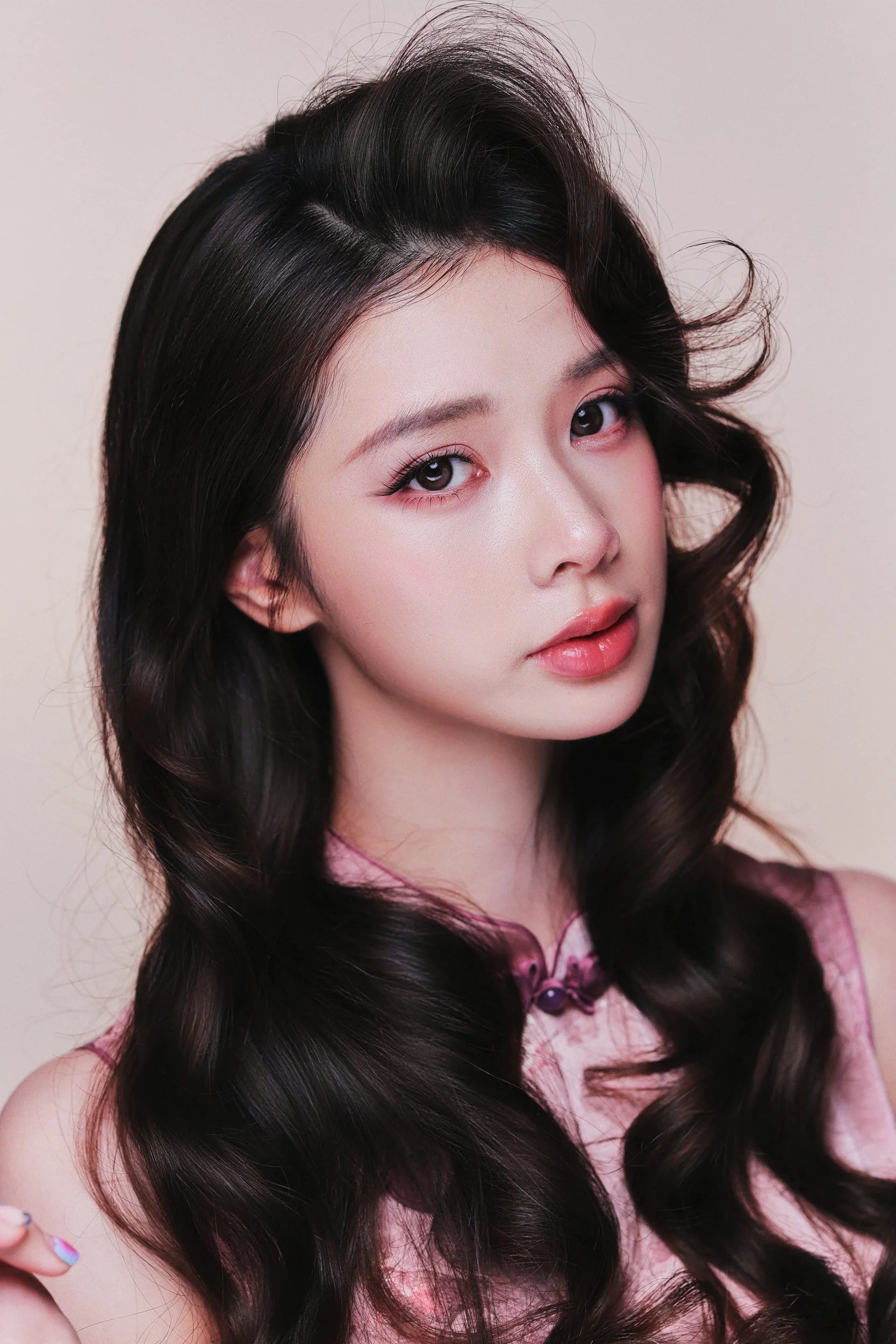 Close-up beauty portrait of a woman with curled dark hair on a pink backdrop