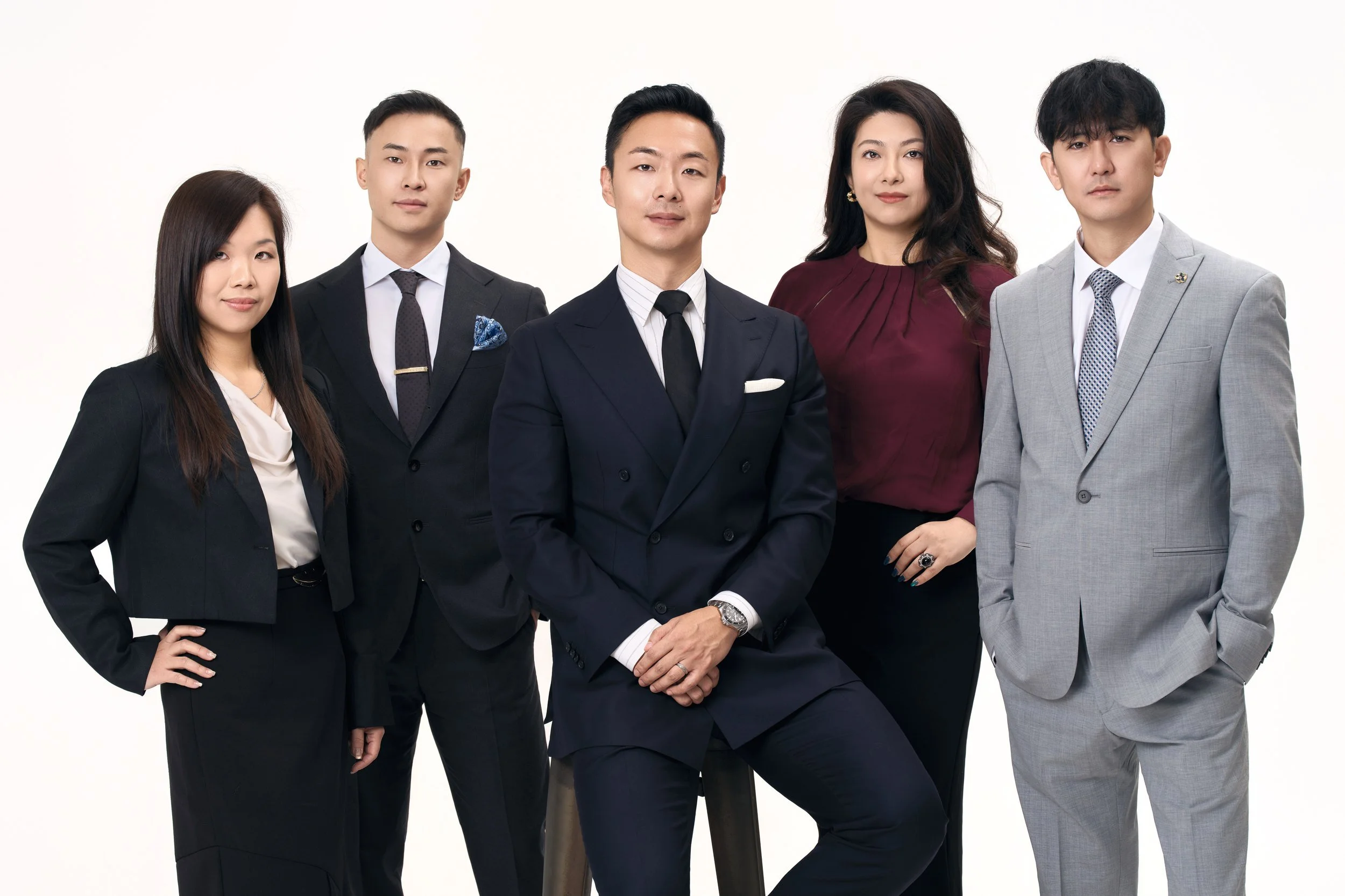 Company team portrait of five colleagues in business attire on a light background