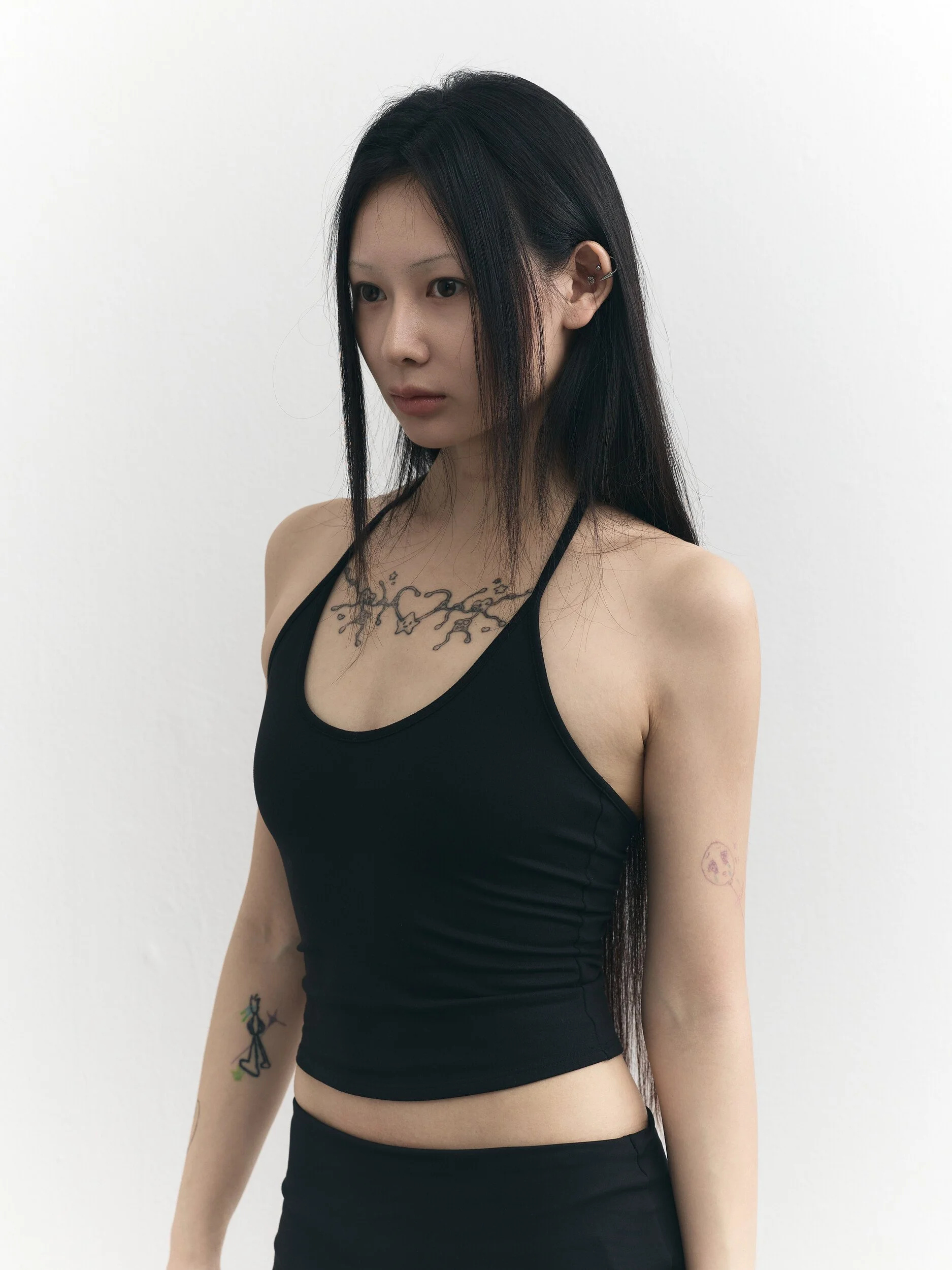 Model digitals: waist-up three-quarter view of the model in a black halter top