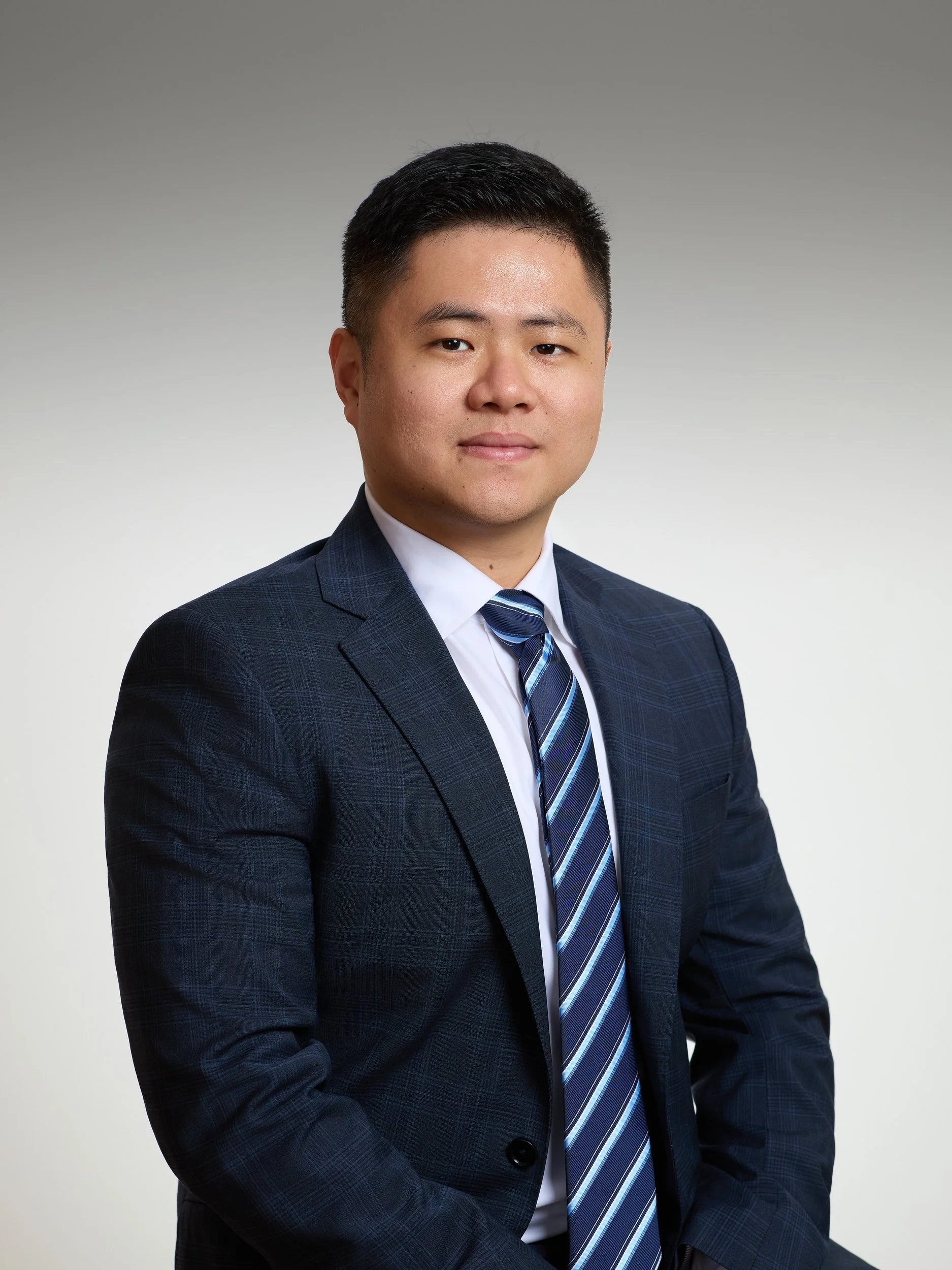 Corporate headshot of a man in a navy suit and blue striped tie