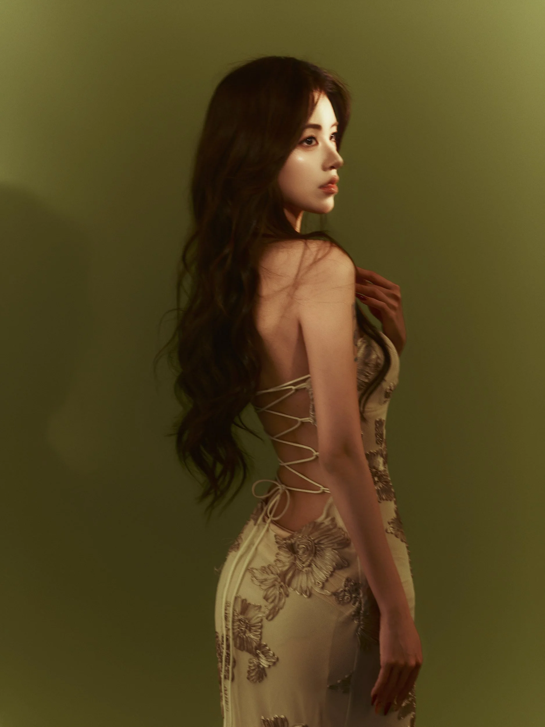 Studio portrait of a woman in a cream strapless top on an olive backdrop