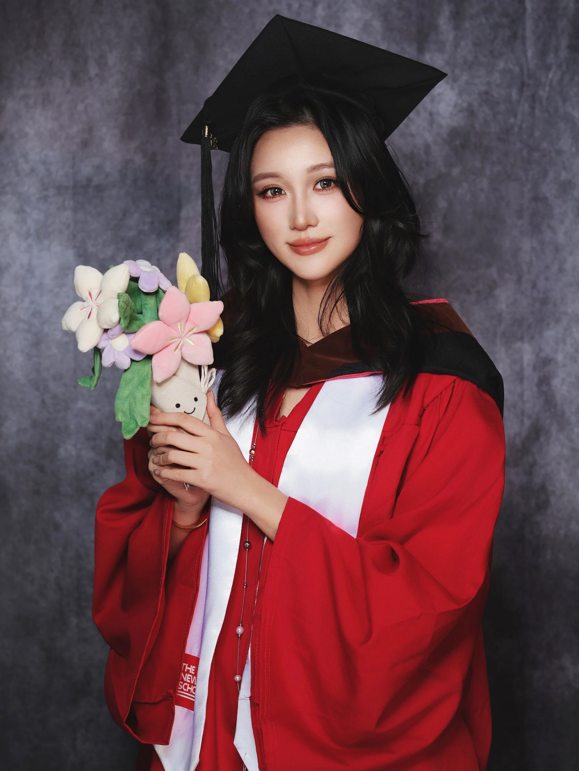 Parsons graduation portrait of a woman in a red gown holding flowers