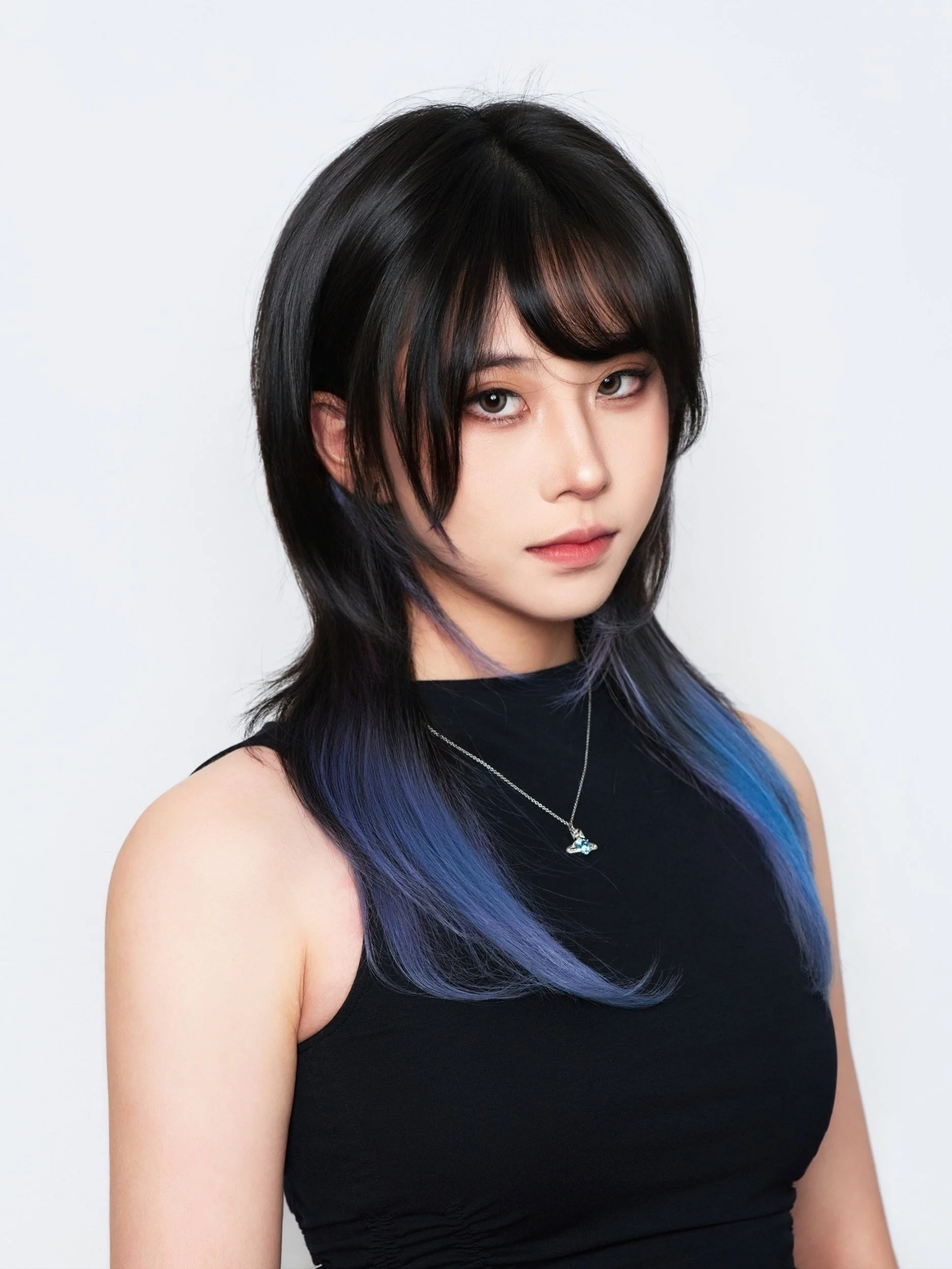 Headshot of a woman with blue-streaked hair in a black sleeveless top