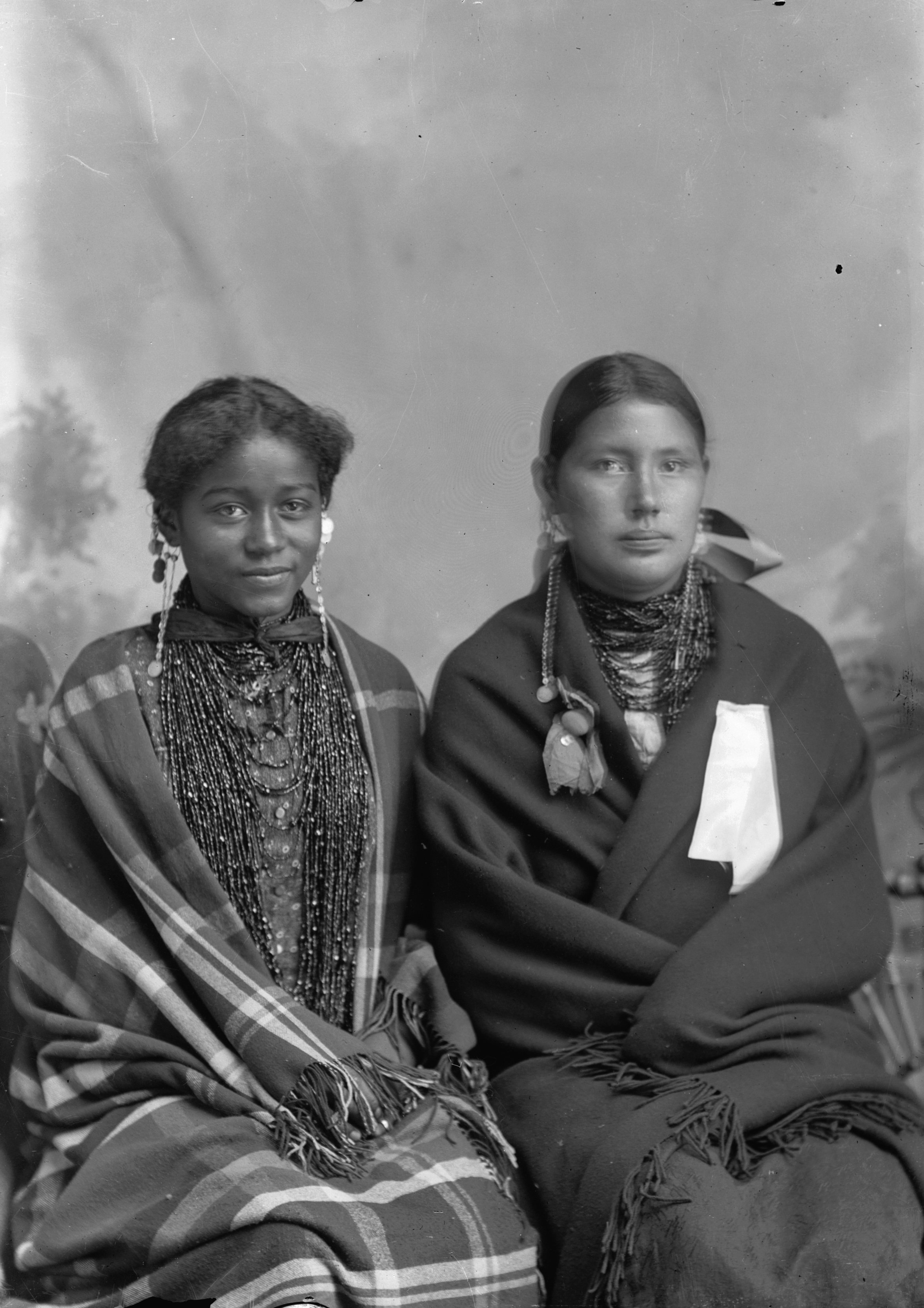 ★ c. early 1900s, Portrait of two young Ho-Chunk women, seated wearing beaded necklaces and wrapped in shawls. Carrie Elk sits on the left, and is of African American and Ho Chunk heritage. Wisconsin Historical Society. Image ID W0127R1.