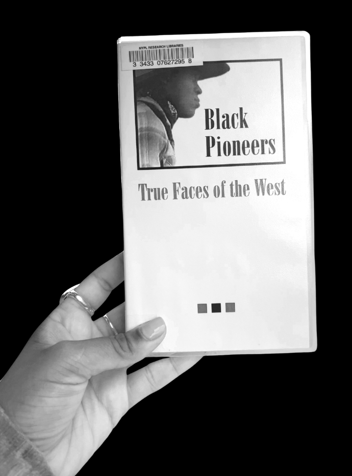 This is an image of a cropped hand holding a vhs copy of the film "Black Pioneers: True Faces of the West" preserved by the Schomburg Center for Research in Black Culture and included in this Black West digital exhibition