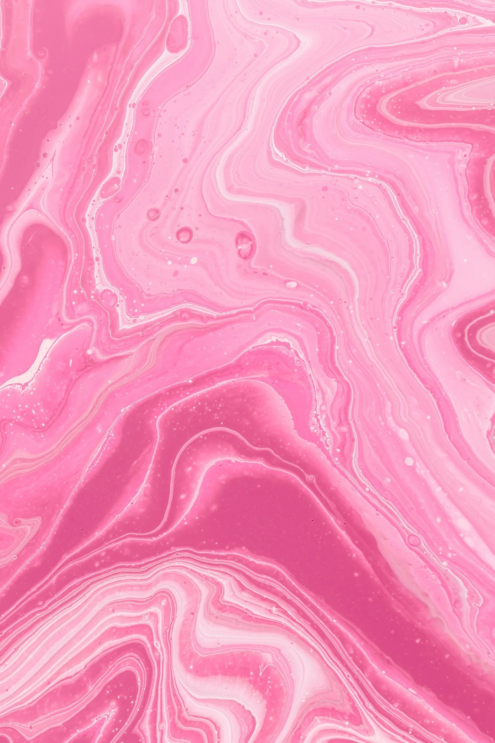 Pink and white marbled abstract background with swirling patterns and small bubbles.