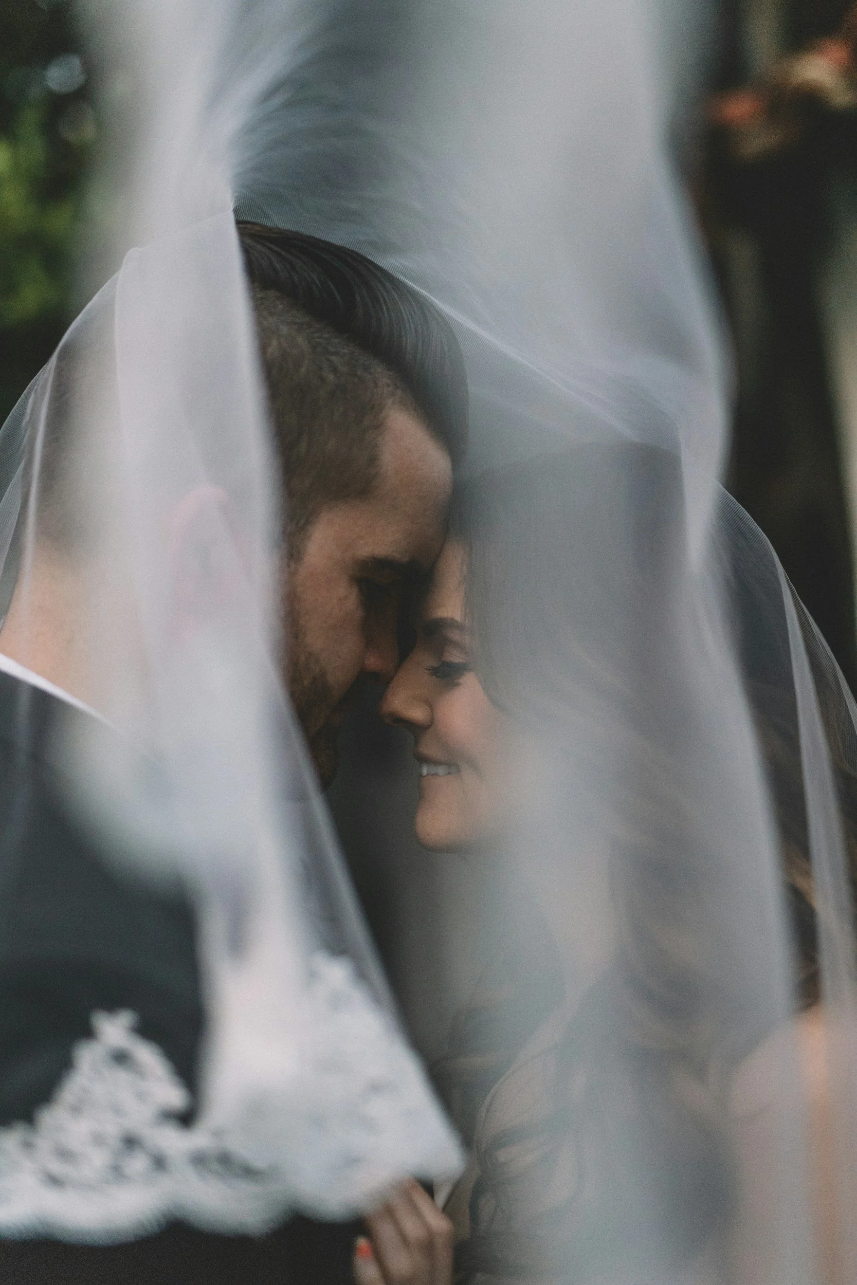 Intimate wedding portrait of bride and groom under the veil, smiling and touching foreheads in Nosara, Costa Rica, by Ines Prelovsek.