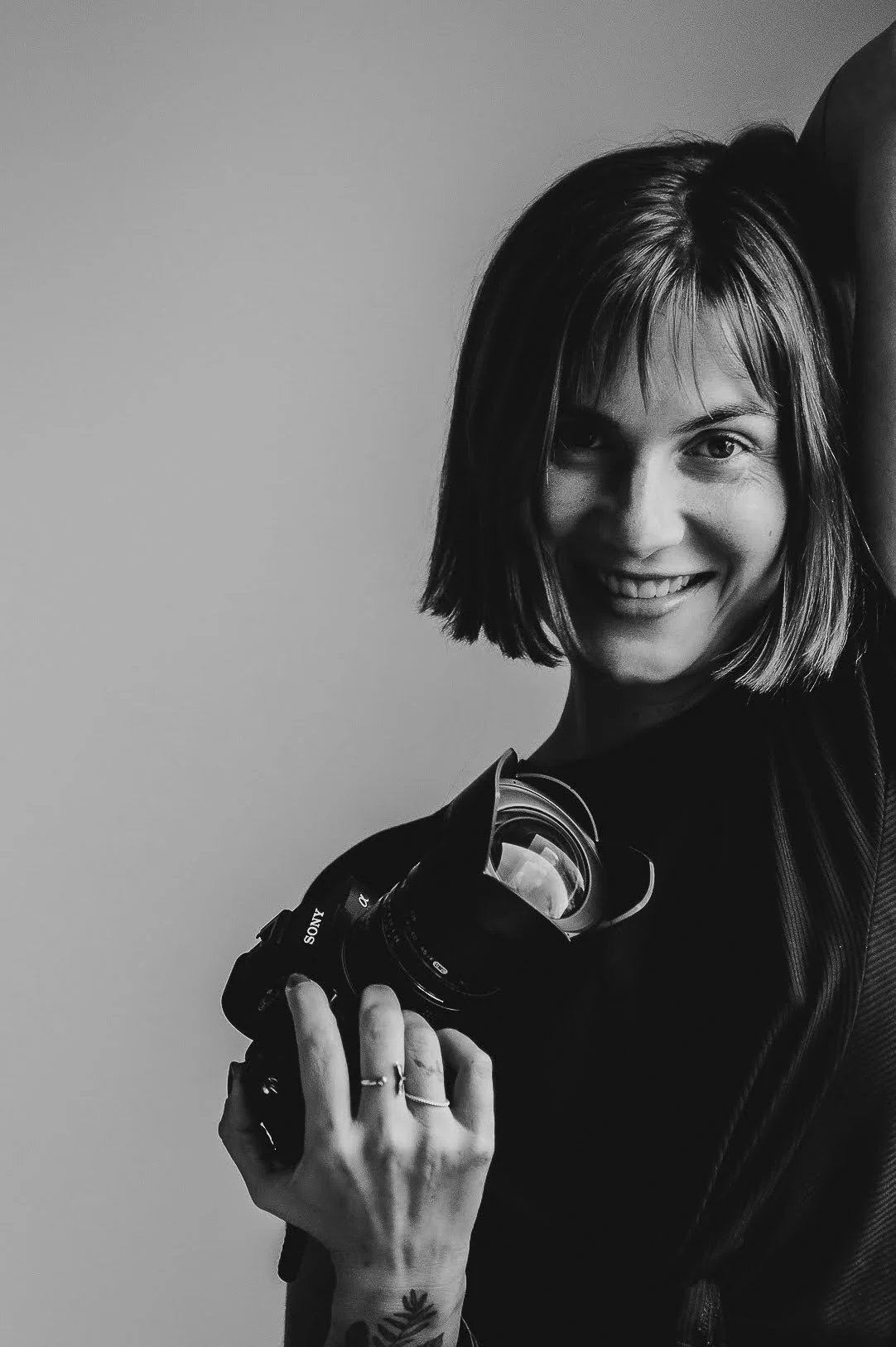Ines Prelovsek photographer in Nosara Costa Rica Black and white photo of a young woman with short hair smiling and holding a camera.