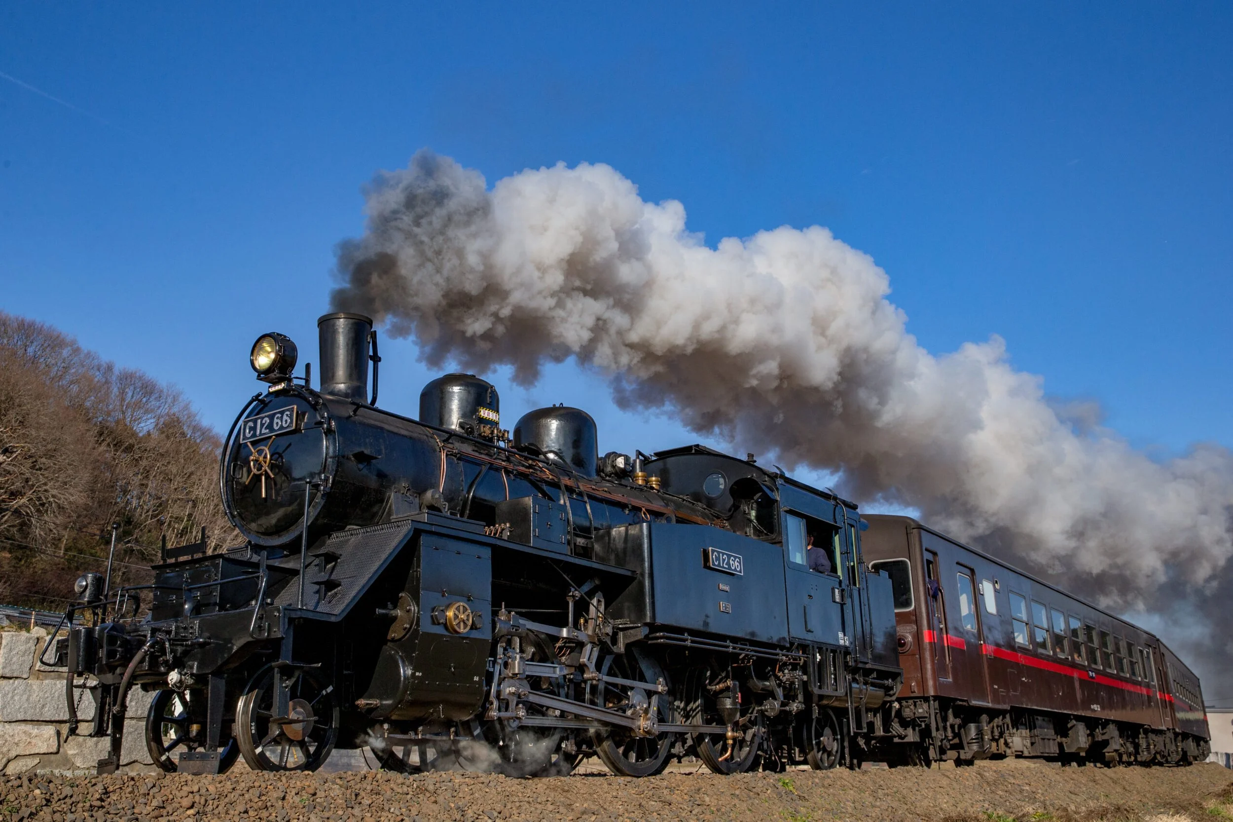 Black C12 66 steam locomotive billowing white smoke under a clear blue sky on Moka Railway — a nostalgic SL journey through rural Tochigi, Japan.