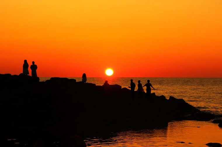 Silhouetted visitors gather on rocky shore as the sun sinks into the Sea of Japan at Ogonmisaki, Rumoi — one of Hokkaido's Best 100 Sunsets.