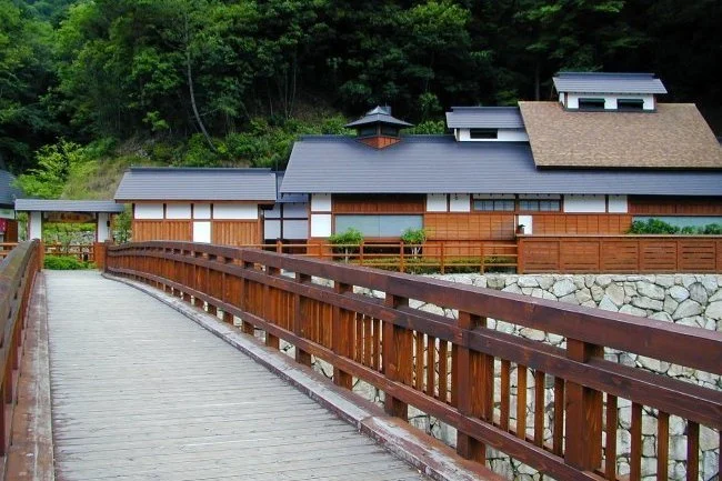 Wooden footbridge leading to a traditional ryokan at Shionoe Onsen, a 1,300-year-old hidden hot spring retreat in the mountains of Kagawa.