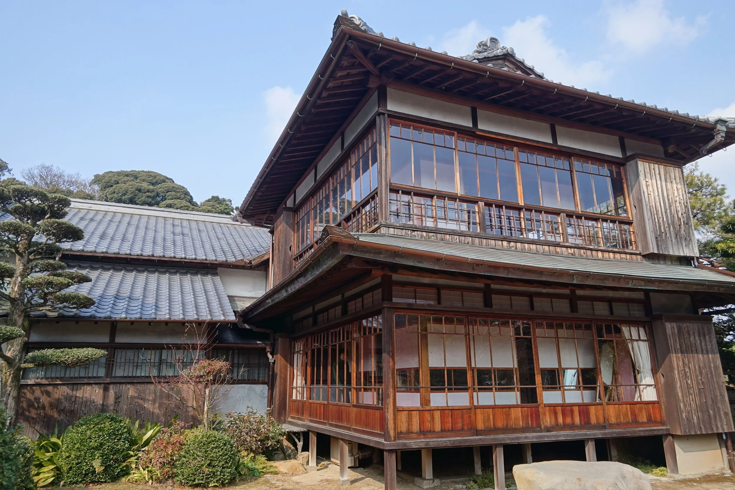 Traditional two-story wooden villa with grey tiled roof and pruned pines at Chofu Garden, a hidden Edo-era samurai retreat in Shimonoseki.