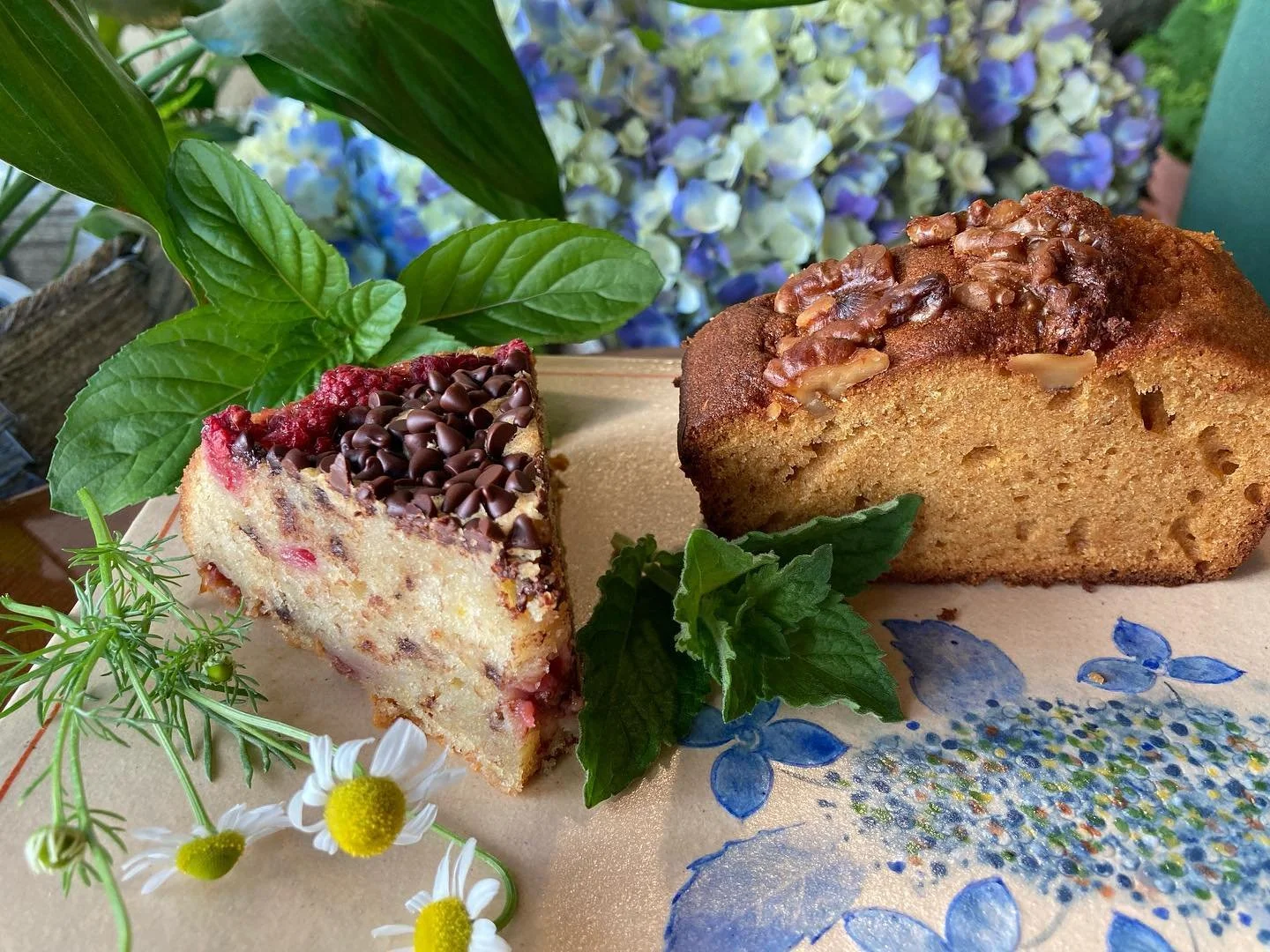 A dessert served in a tall glass with various toppings like fruit, beans, and cookies, viewed on a tray with a blurred background.