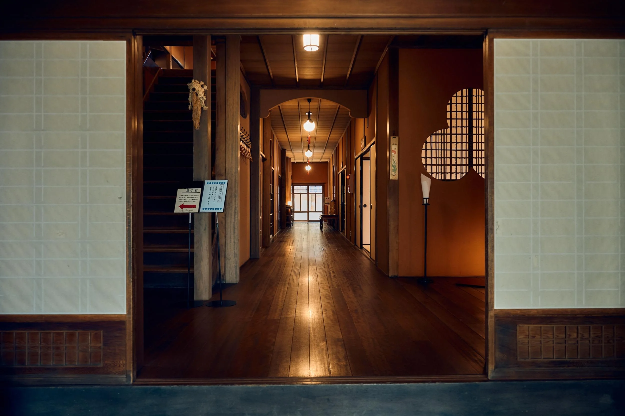 A dessert served in a tall glass with various toppings like fruit, beans, and cookies, viewed on a tray with a blurred background.