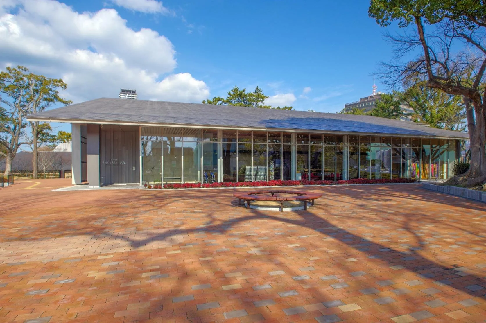 A modern building with glass doors and windows, decorated with flags and signs, including a cartoon tiger mascot wearing a white hat and cape, outdoors on a sunny day with trees in the background.