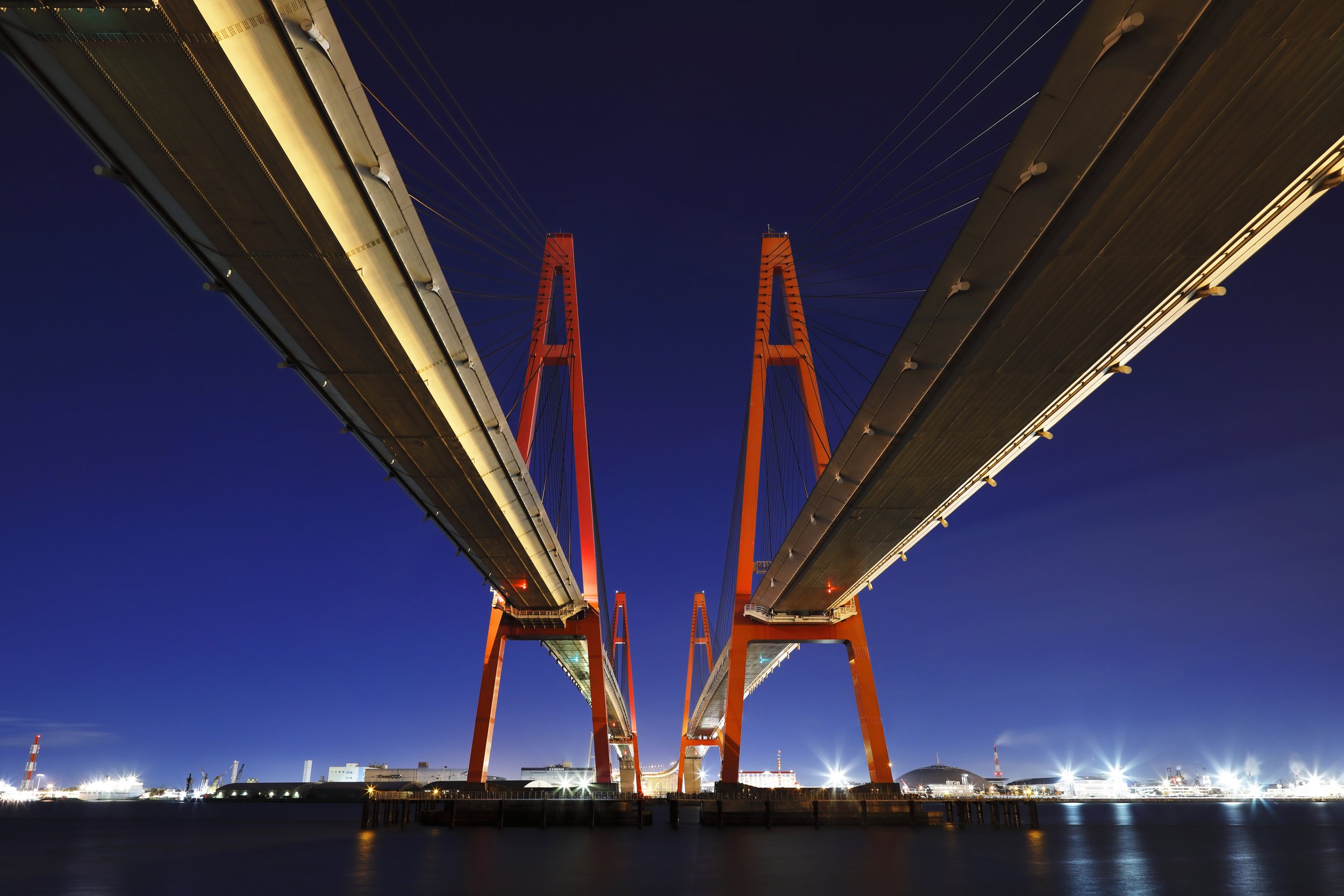 Red-pyloned Triton Bridge reflected on Nagoya Port at night — an industrial nightscape cruise hidden gem in Tobishima Village, Aichi.