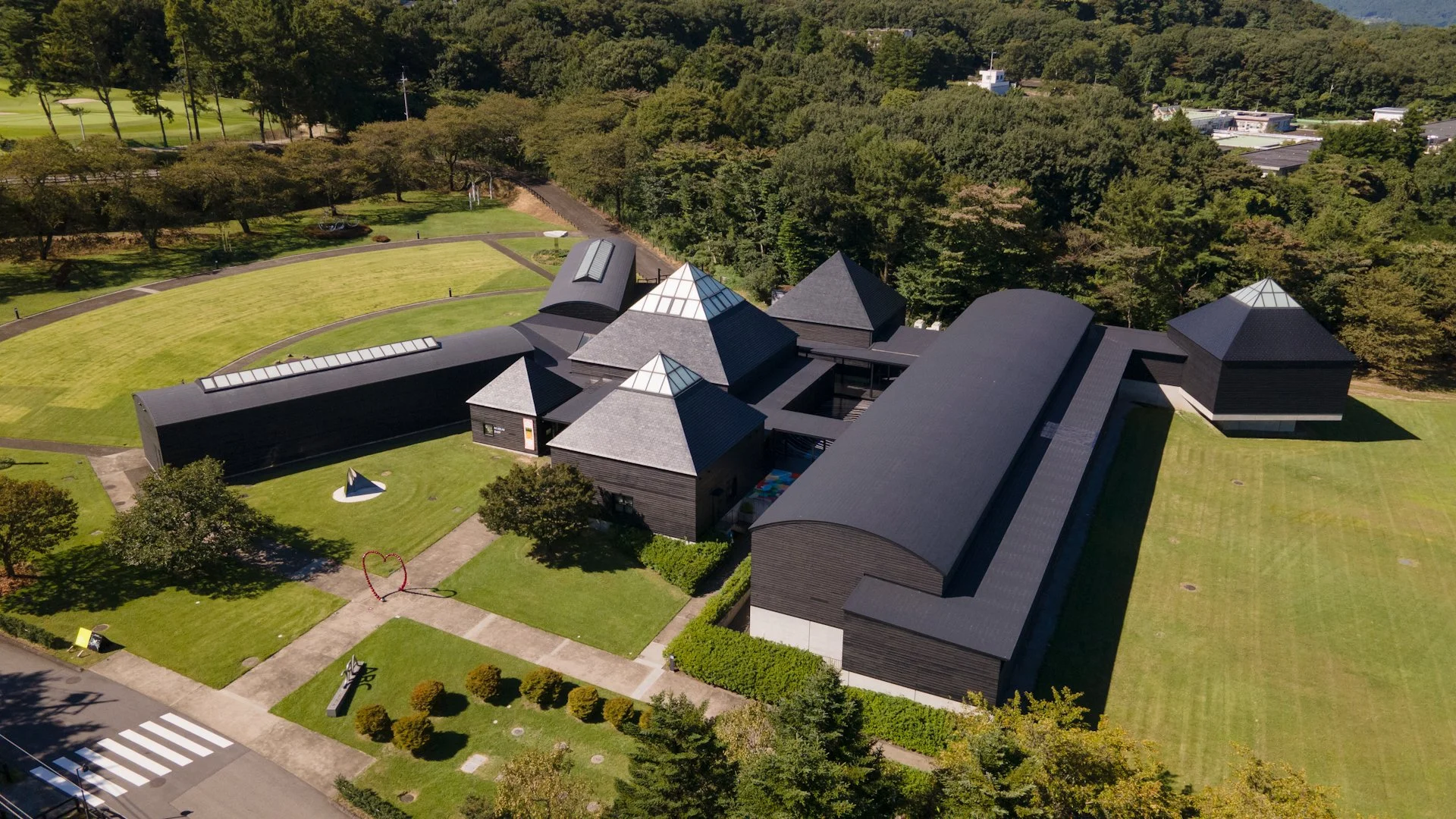 Aerial view of Hara Museum ARC in Gunma — Arata Isozaki's dark-roofed pavilions and sculpture gardens nestled among forested hills.