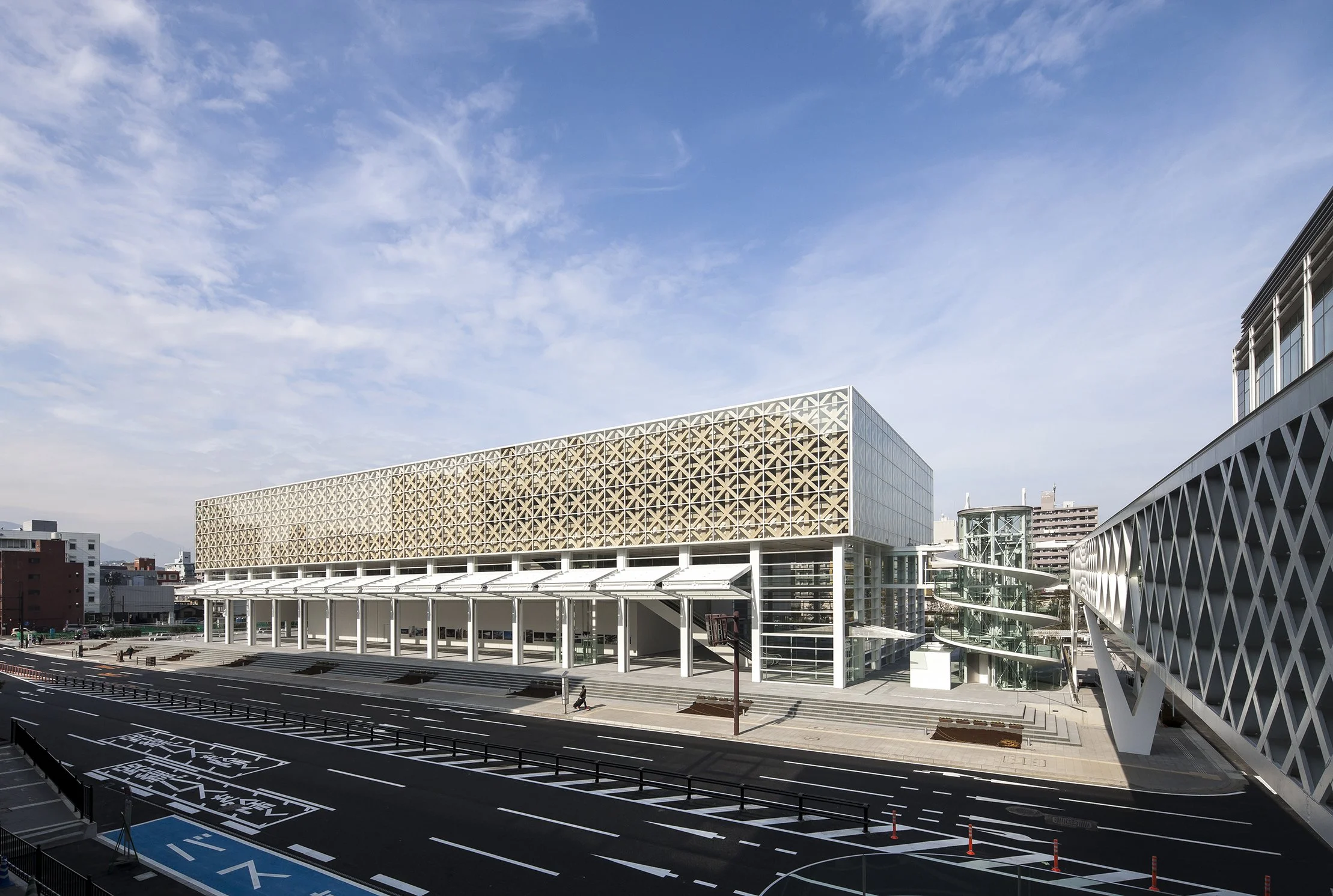 OPAM's bamboo-inspired lattice facade by Shigeru Ban gleaming under clear blue skies in central Oita City.