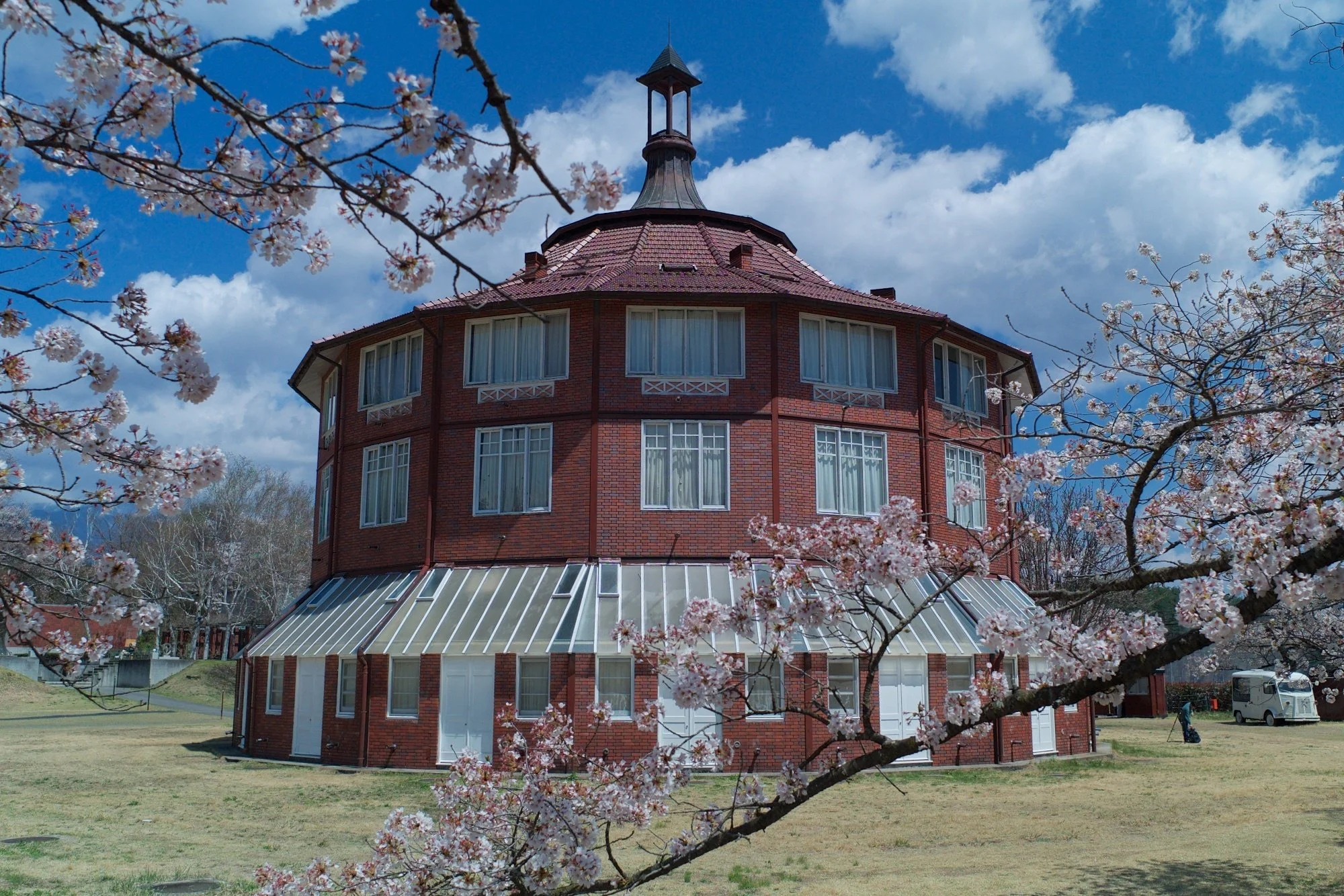 Red-brick La Ruche atelier framed by pale cherry blossoms at Kiyoharu Art Colony, Yamanashi — a hidden gem for art lovers in Japan.