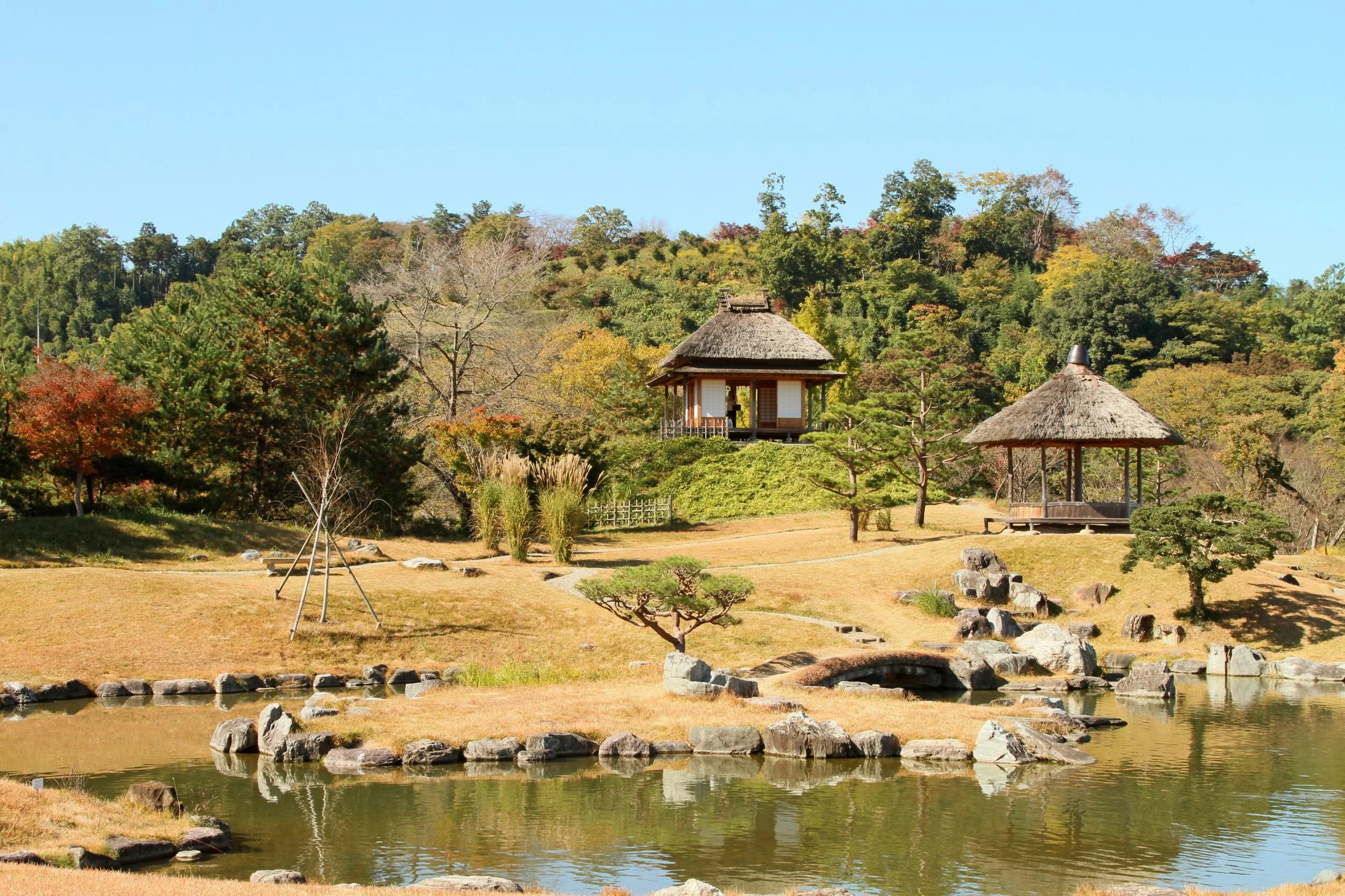 Thatched-roof pavilions overlooking a still pond and autumn hills at Rakusanen, a hidden Edo-era daimyo garden in Gunma.