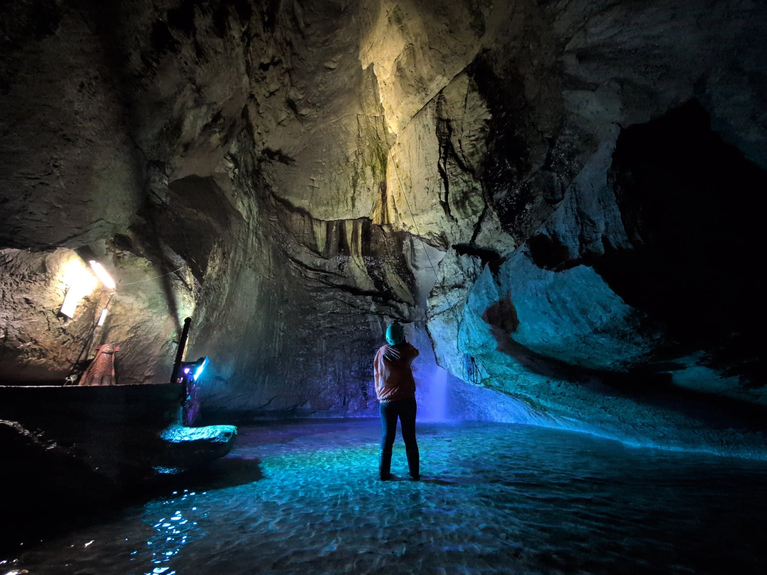 A lone explorer stands in a vast blue-lit underground cavern at Rokando Cave, Iwate — one of Japan's most extraordinary hidden gems.