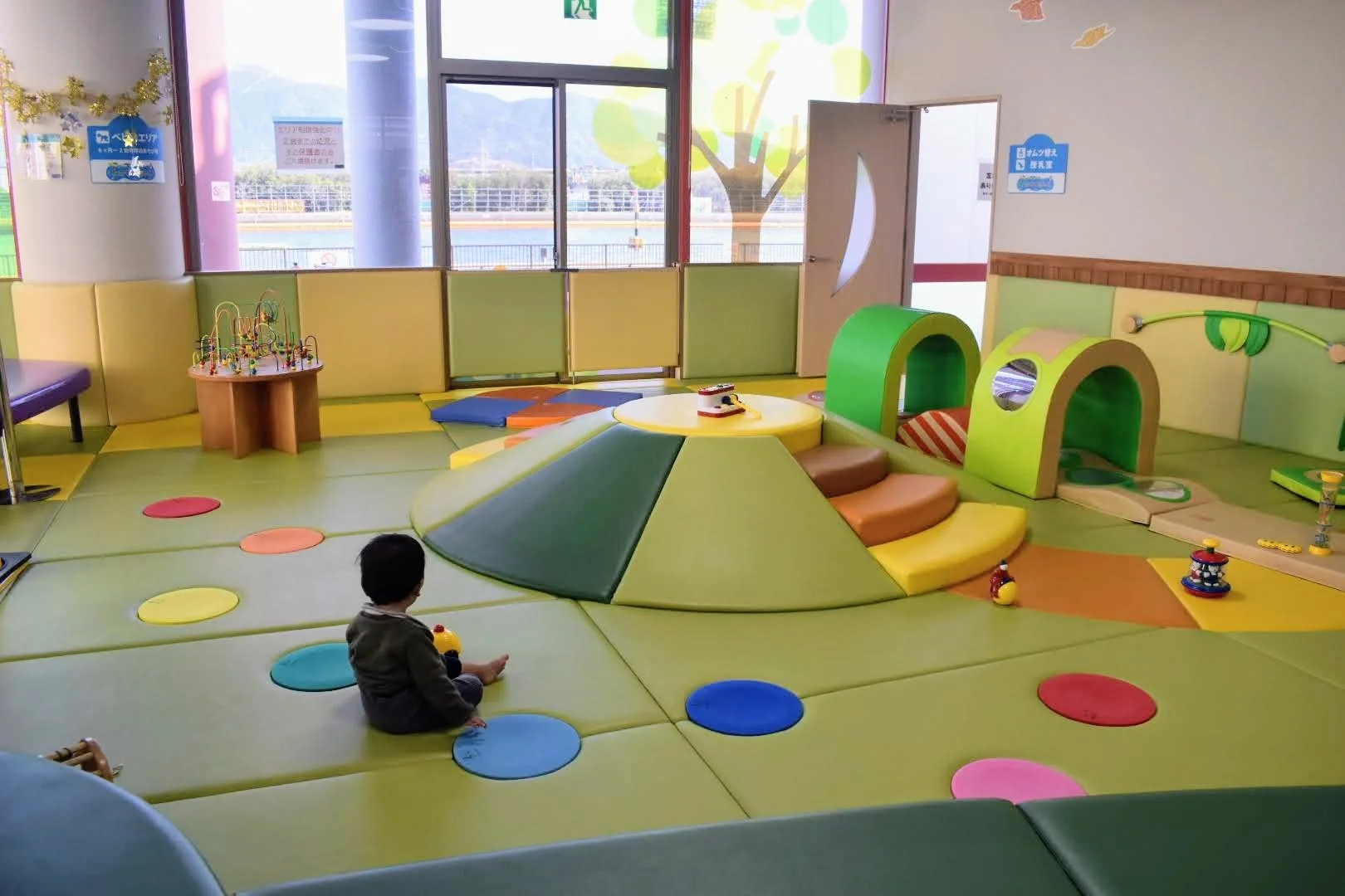A bowl of udon noodle soup topped with green onions, tempura, beef, and a fish cake, served alongside onigiri rice balls wrapped in seaweed.
