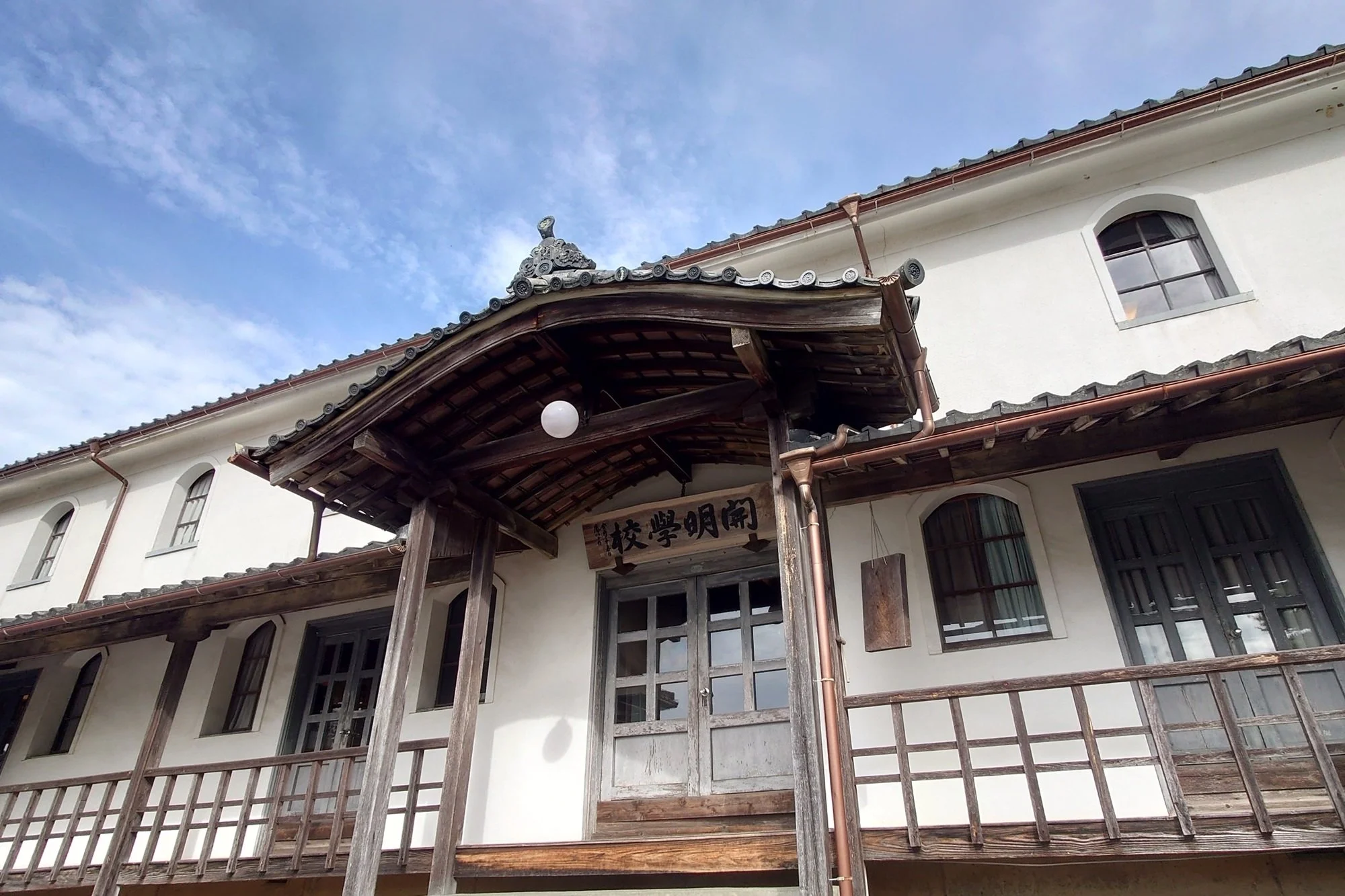 White plaster and weathered wood facade of Kaimei School in Ehime — western Japan's oldest Meiji-era wooden school building, a hidden gem in rural Shikoku.