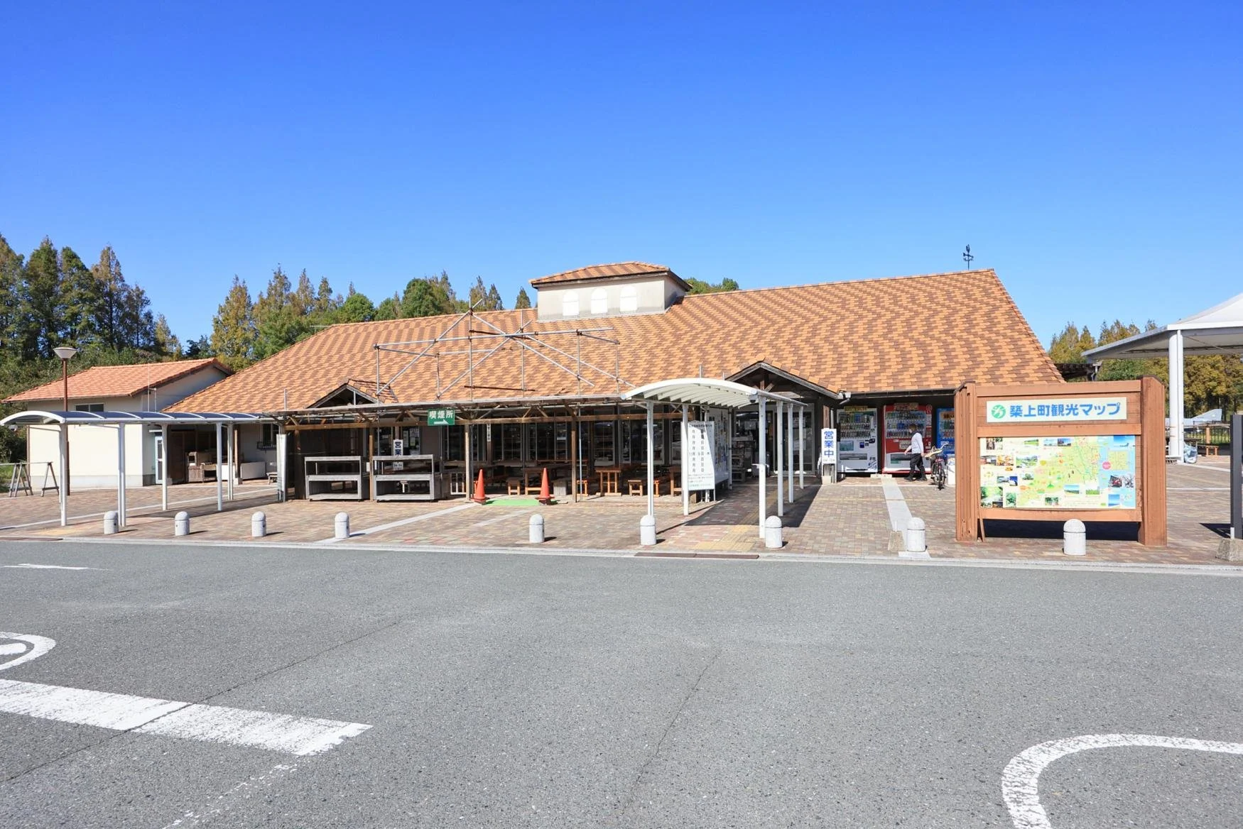 Metase no Mori roadside station in Chikujō, Fukuoka — red-tiled roof buildings and open plaza under a clear blue sky, surrounded by metasequoia trees.