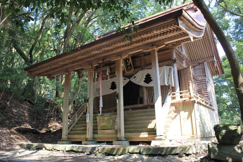 Weathered wooden hall of Kunitama Shrine on Mount Kubote, Fukuoka, framed by ancient forest and white drapes — a hidden Shugendo sanctuary.
