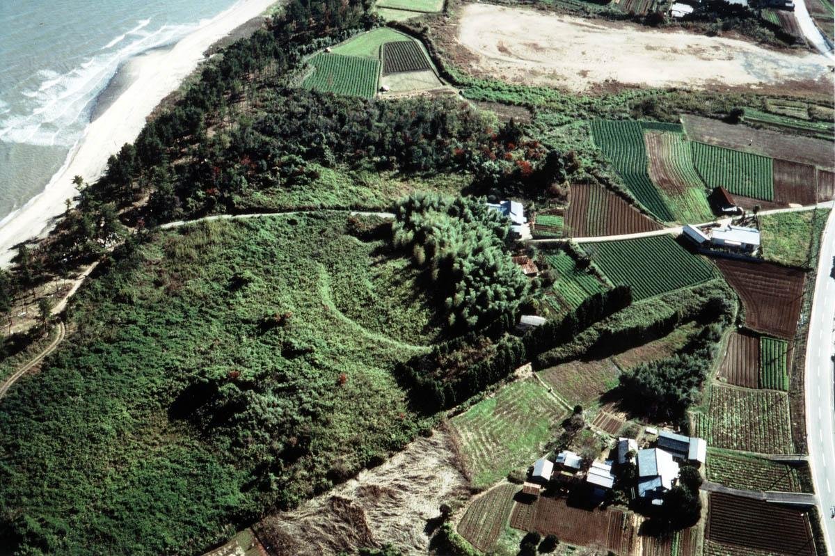 Aerial view of the Inado Kofun Cluster in Yukuhashi, Fukuoka—ancient burial mounds on a green coastal terrace overlooking the sea.