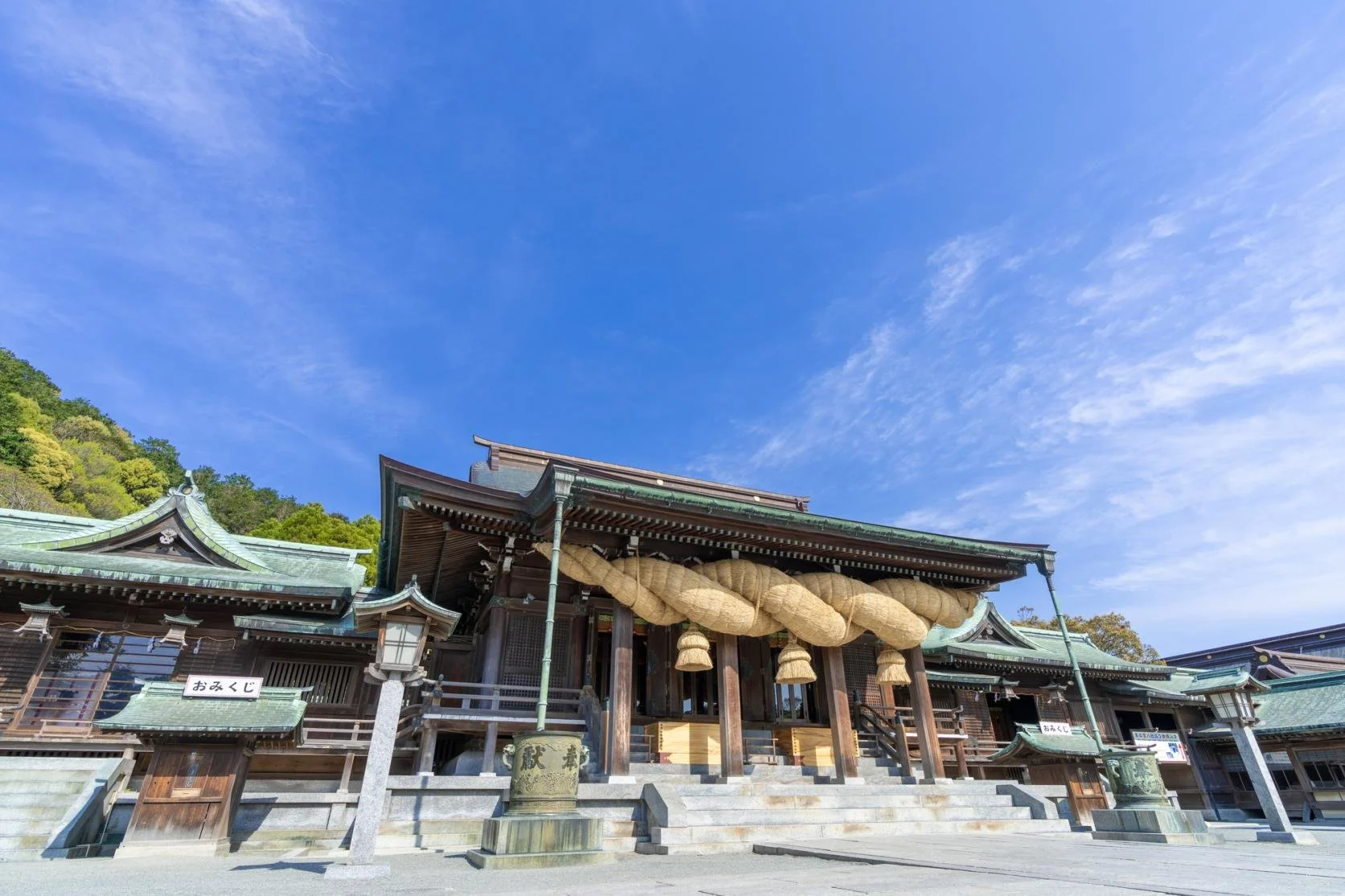 Miyajidake Shrine's main hall in Fukutsu, Fukuoka, framed by Japan's largest shimenawa rope under a bright blue sky.