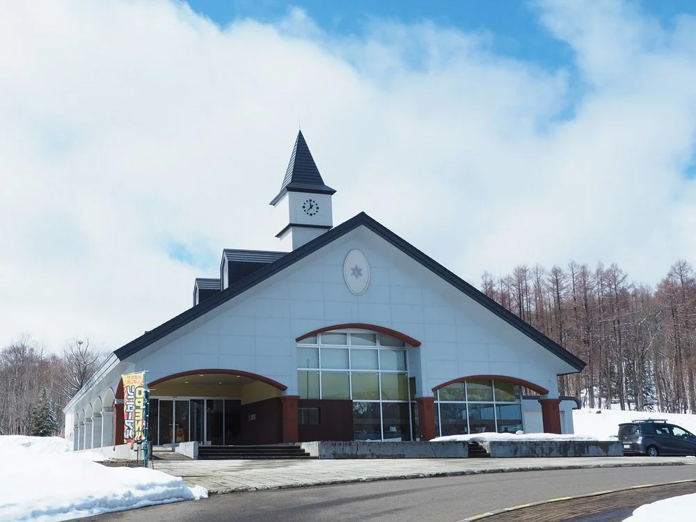 Snow-dusted roadside retreat with clock tower at Michi-no-Eki Mori to Mizuumi no Sato Horokanai, gateway to Hokkaido's soba country and Mt. Santō onsen.