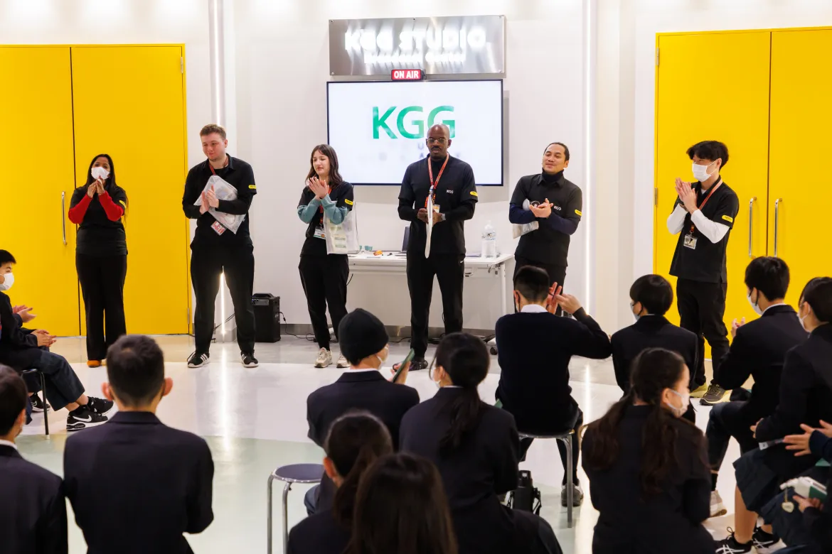 International staff and uniformed Japanese students engaging in hands-on English learning at Kitakyushu Global Gateway, Western Japan's first English immersion facility.